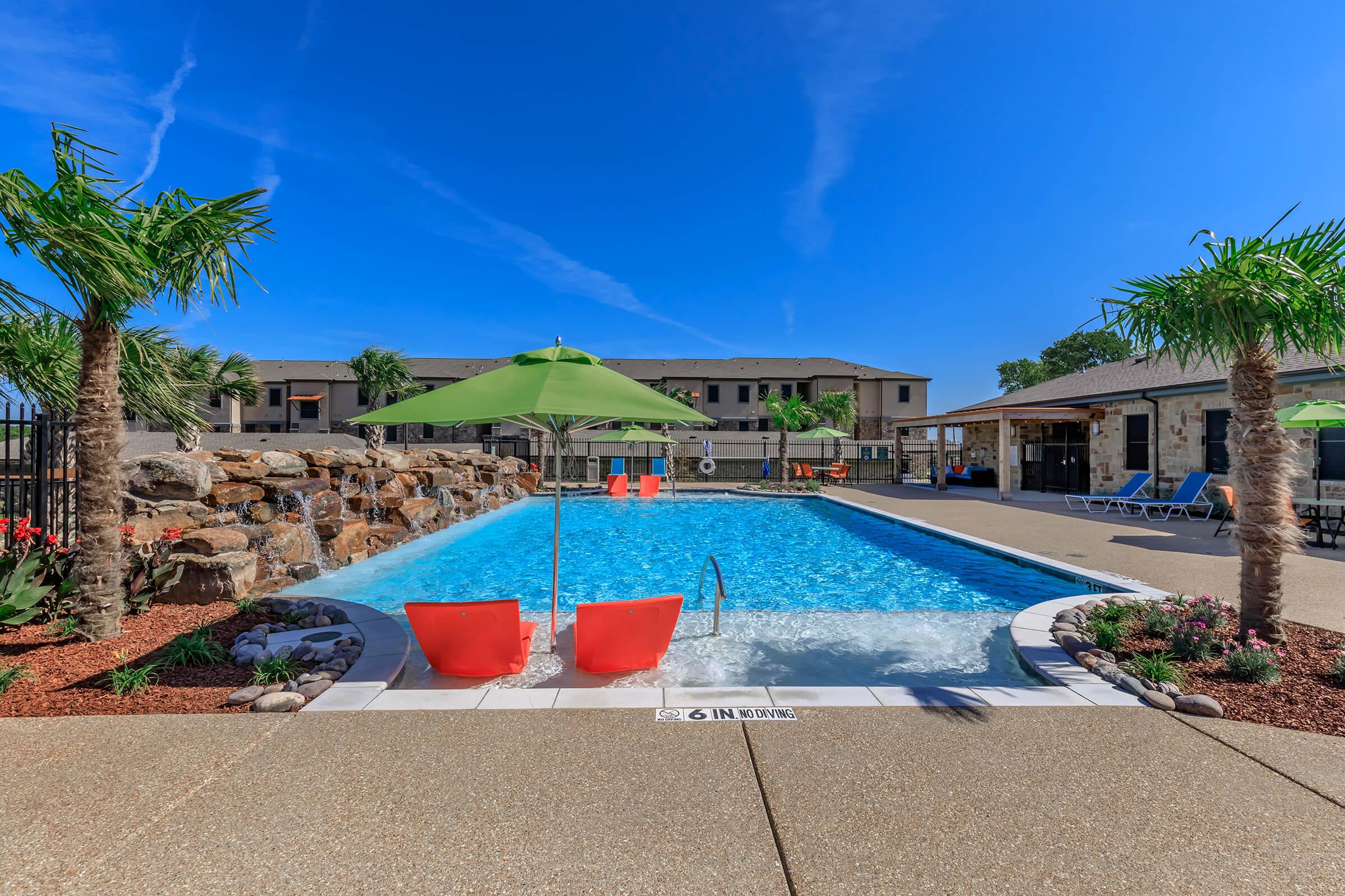 a pool next to a palm tree in front of a building