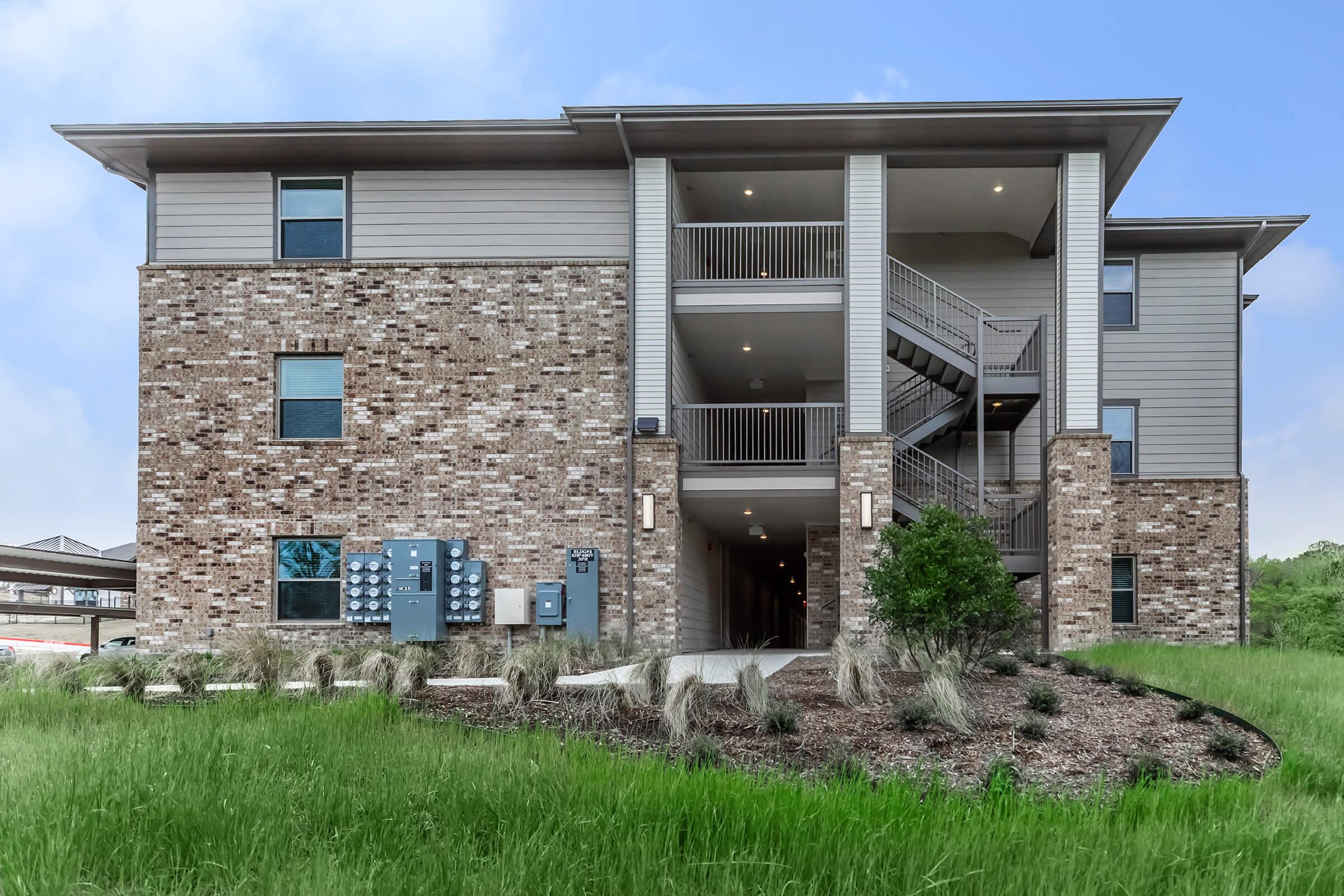 a large brick building with grass in front of a house