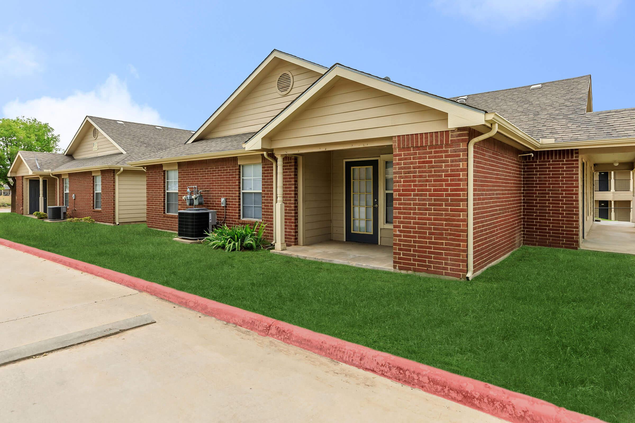 a large brick building with grass in front of a house