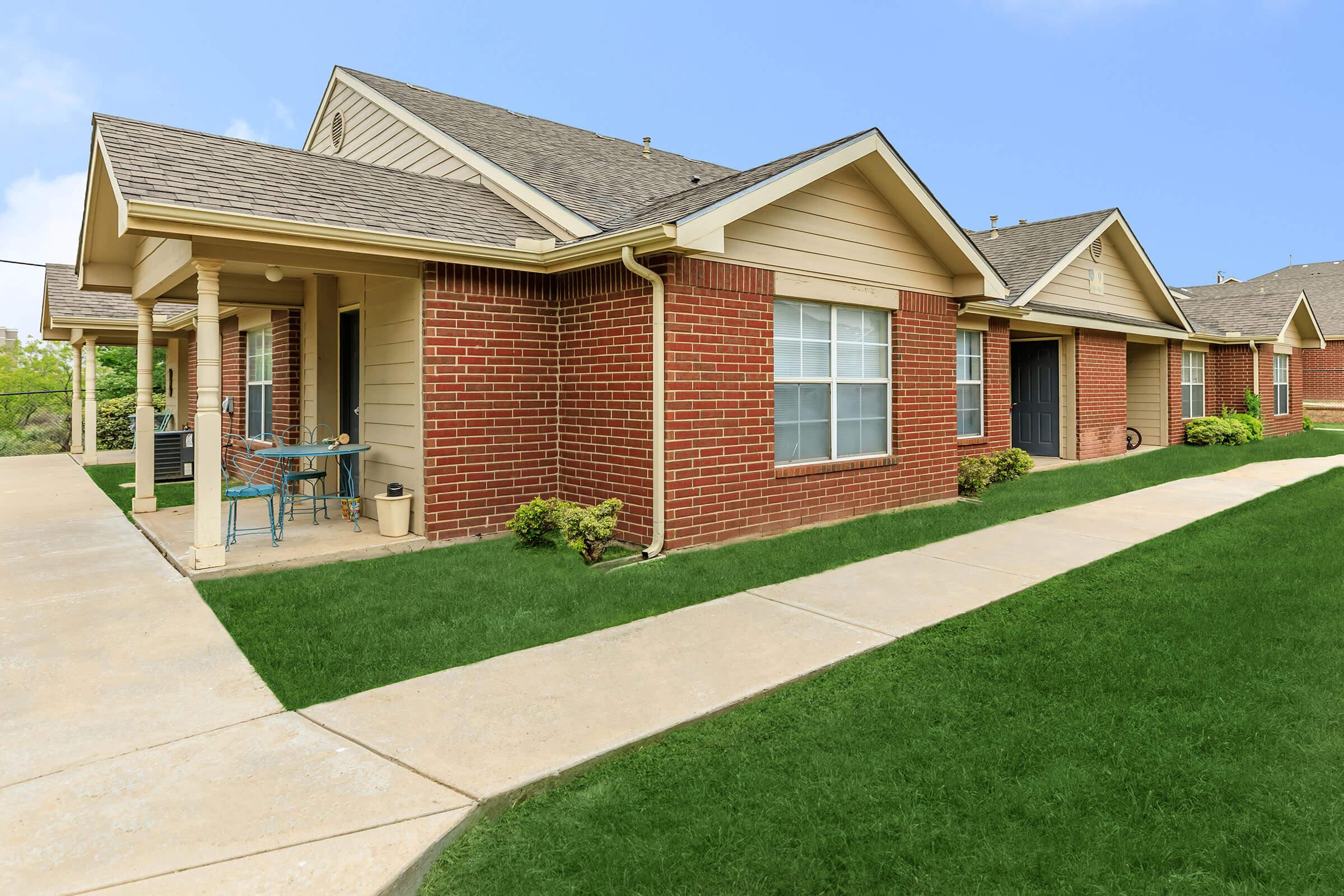 a large brick building with grass in front of a house