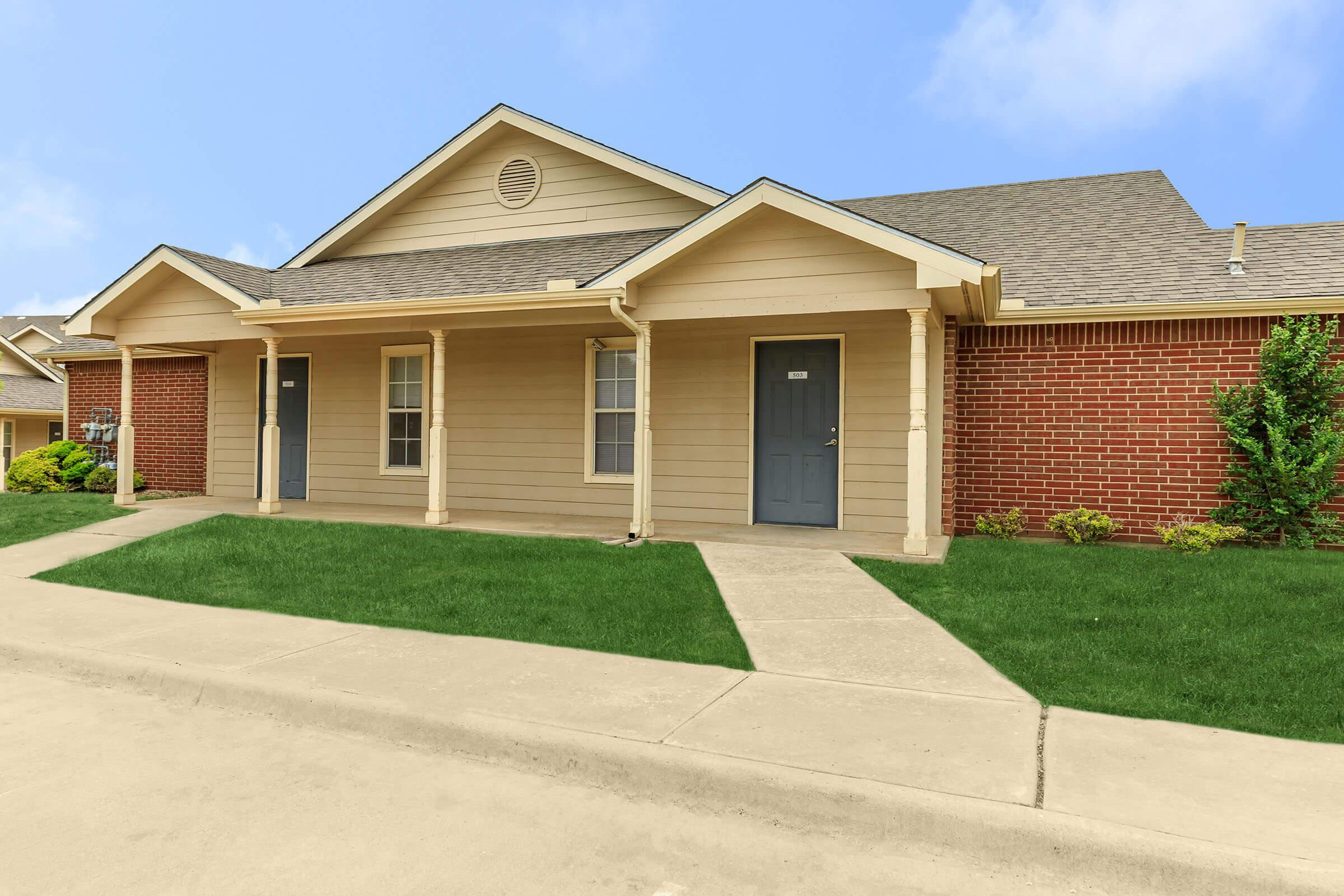 a large brick building with grass in front of a house