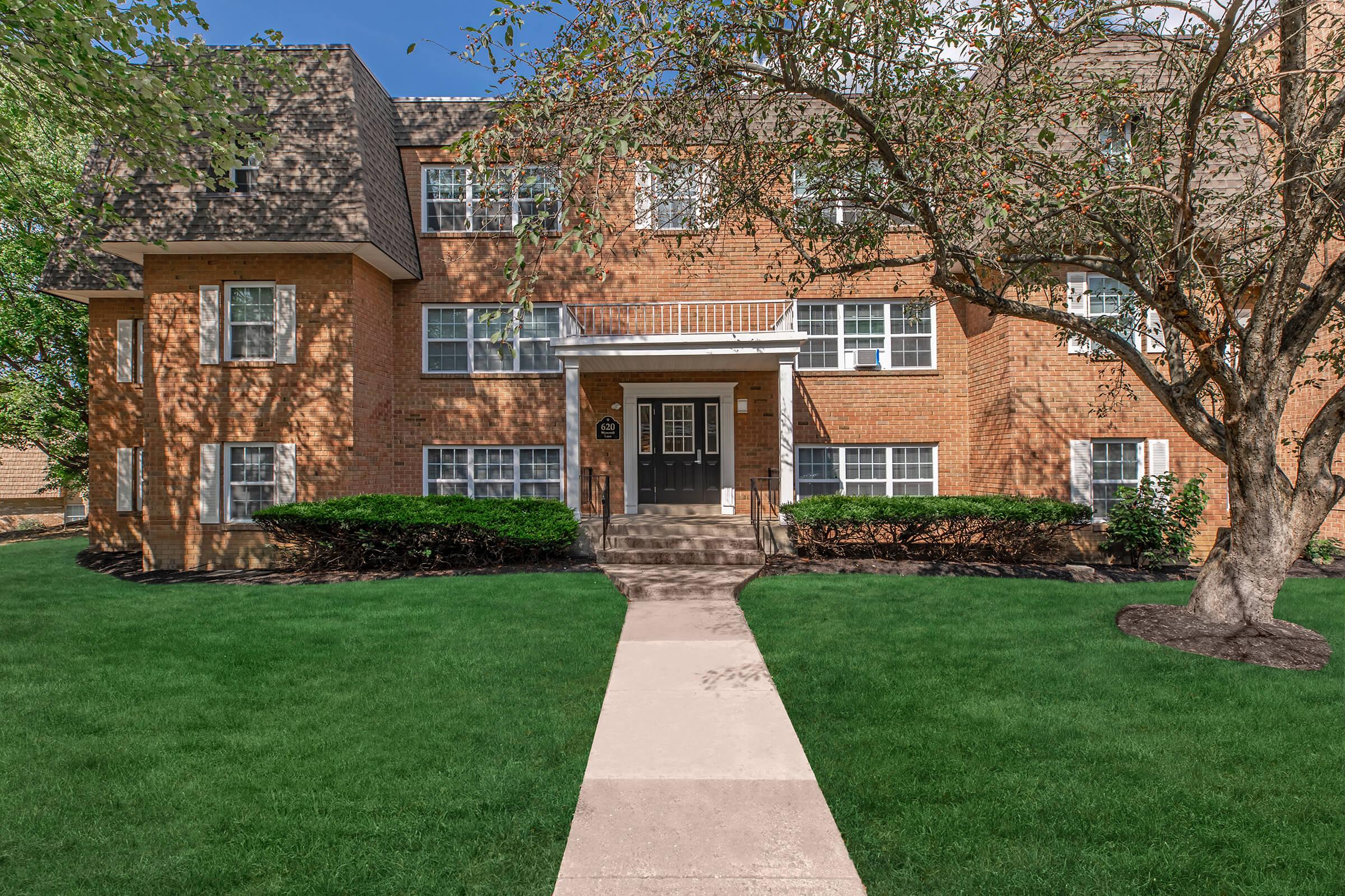 a house with a lawn in front of a brick building