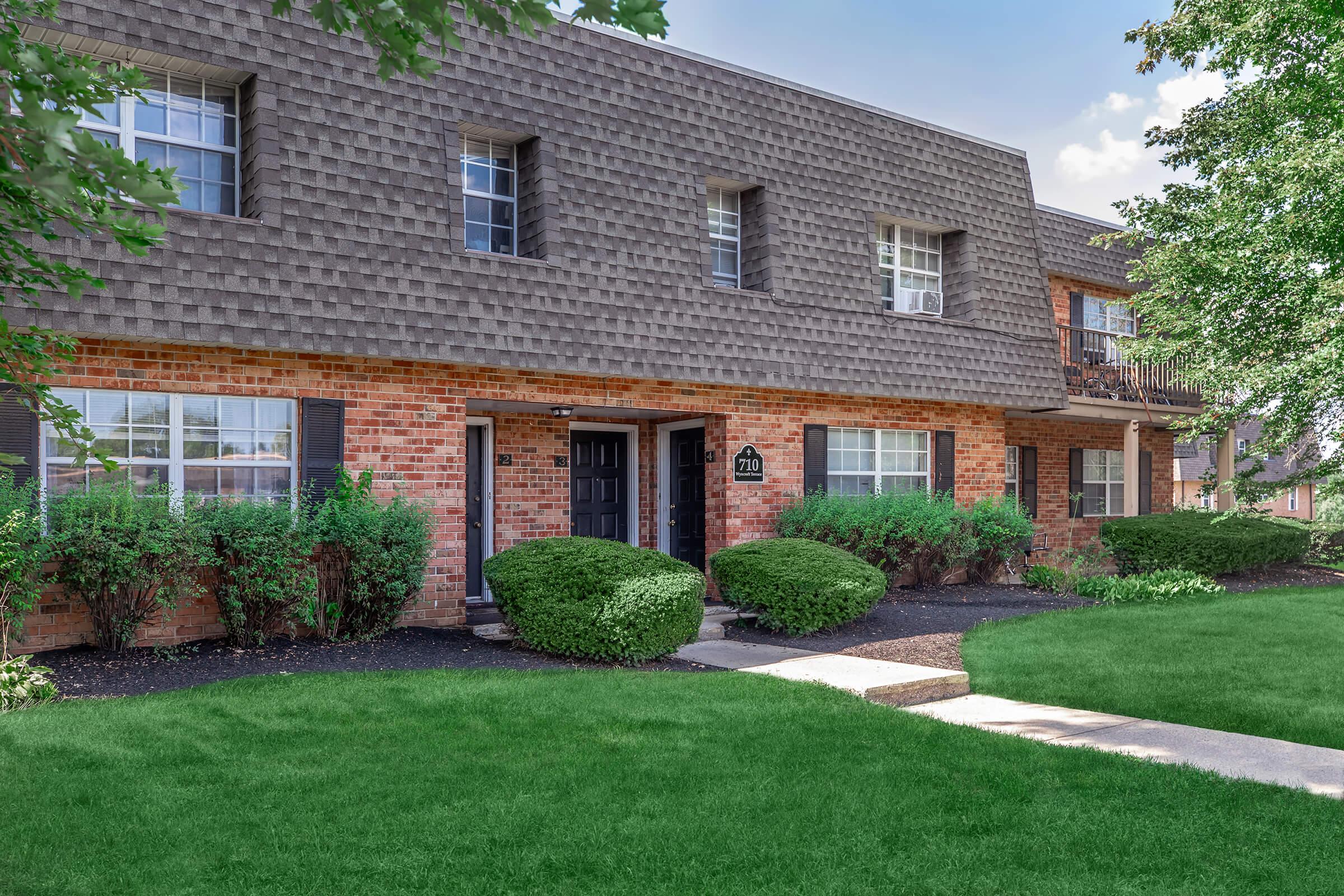 a house with a lawn in front of a brick building