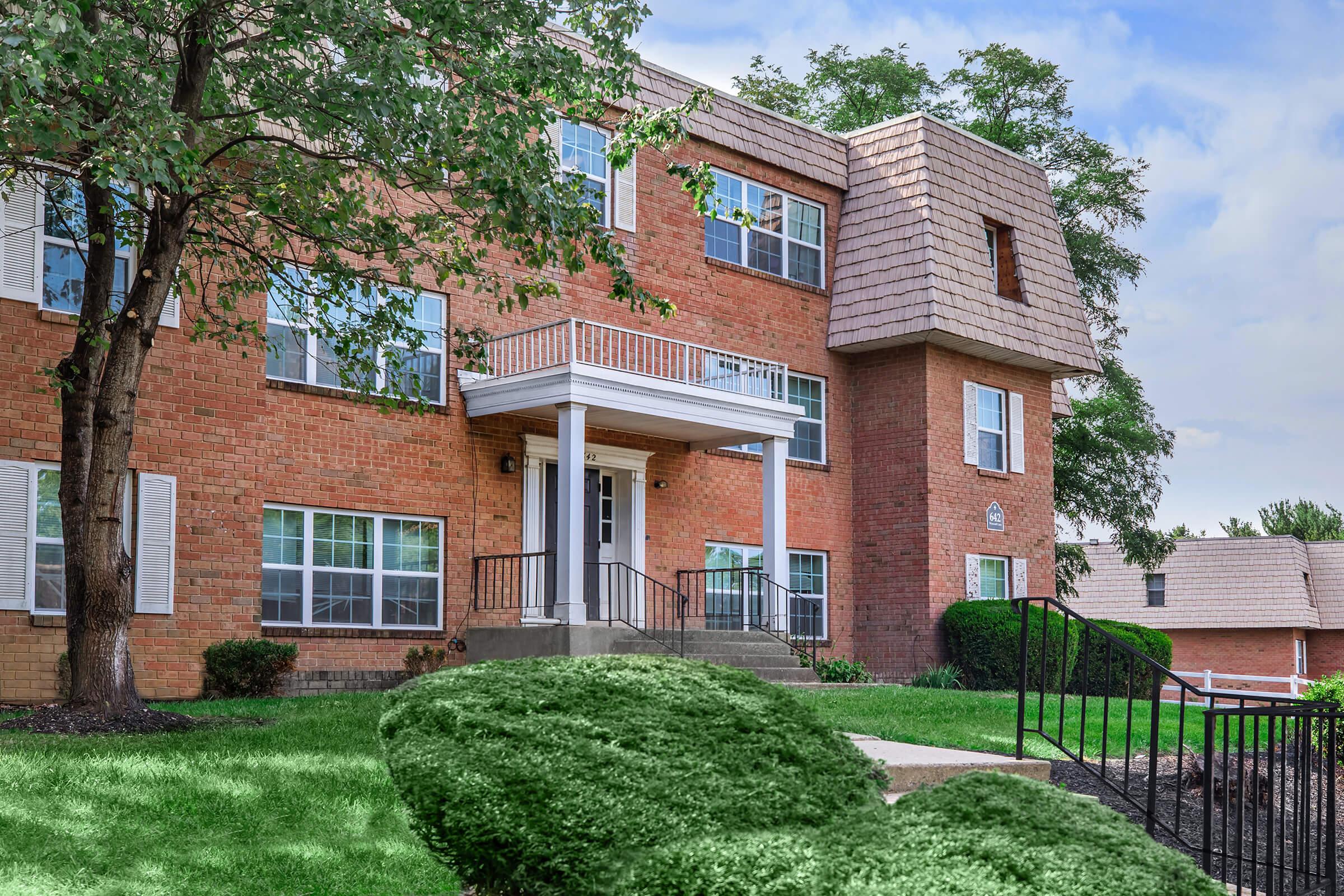 a large brick building with grass in front of a house