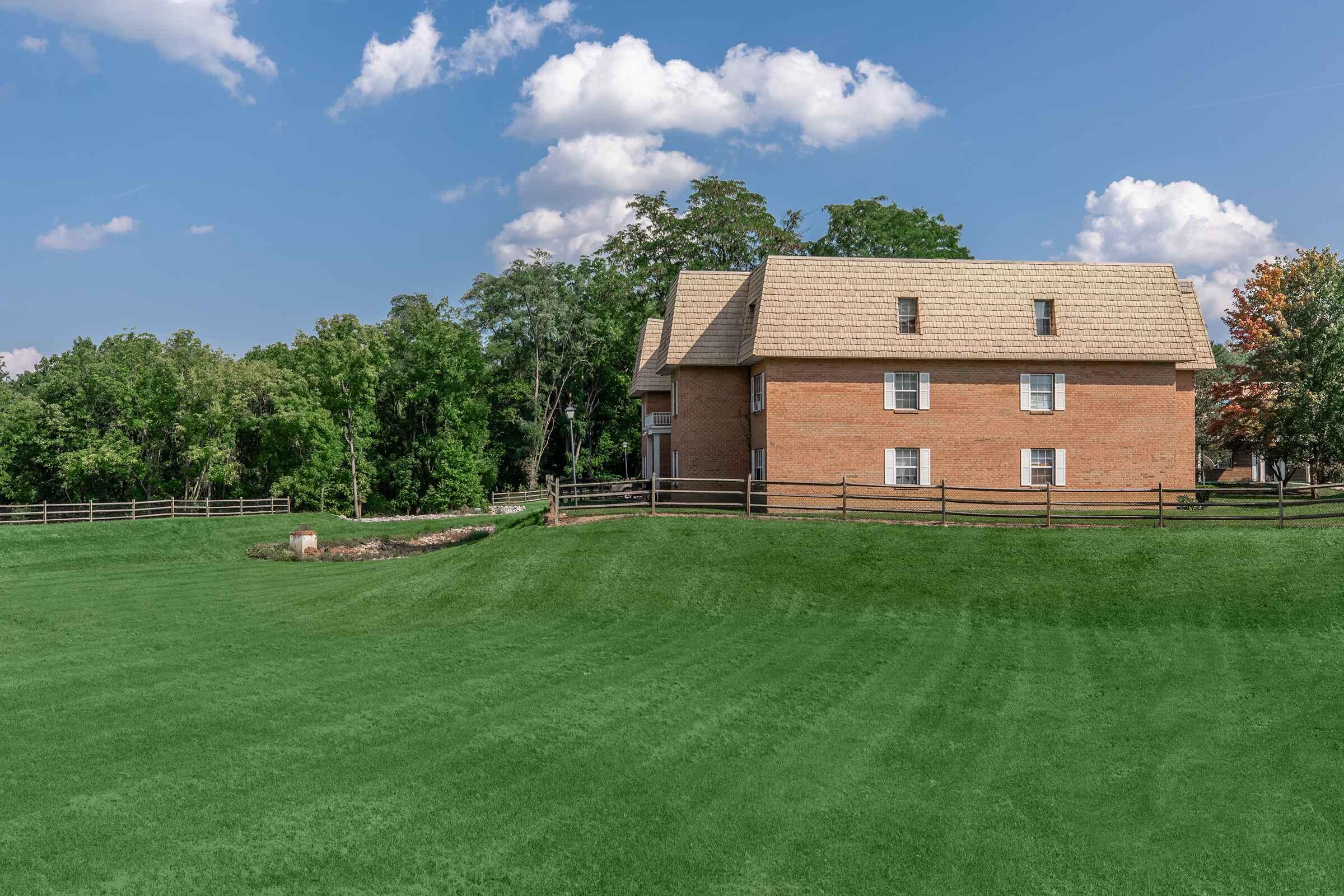 a large brick building with a grassy field