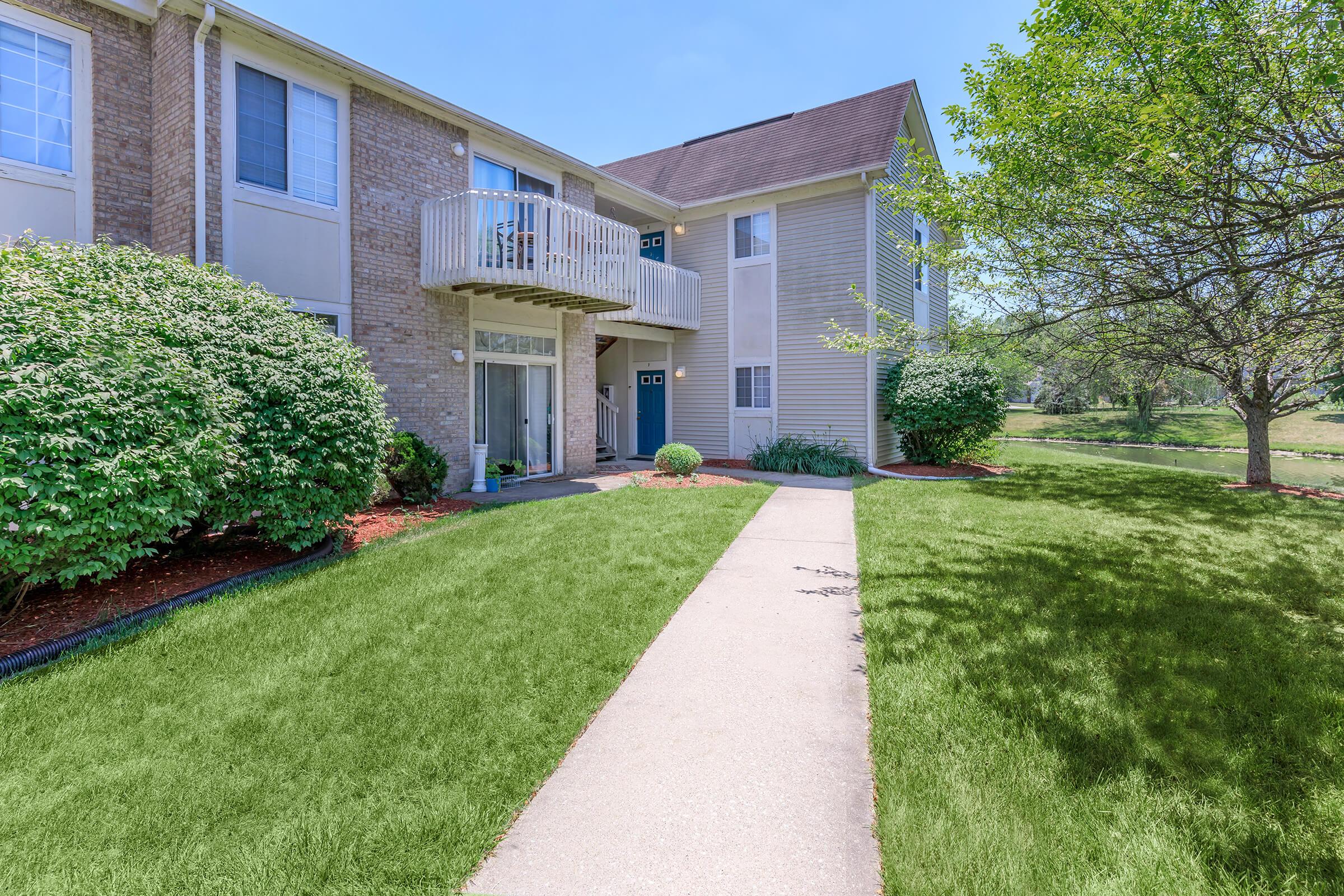 a large brick building with green grass in front of a house