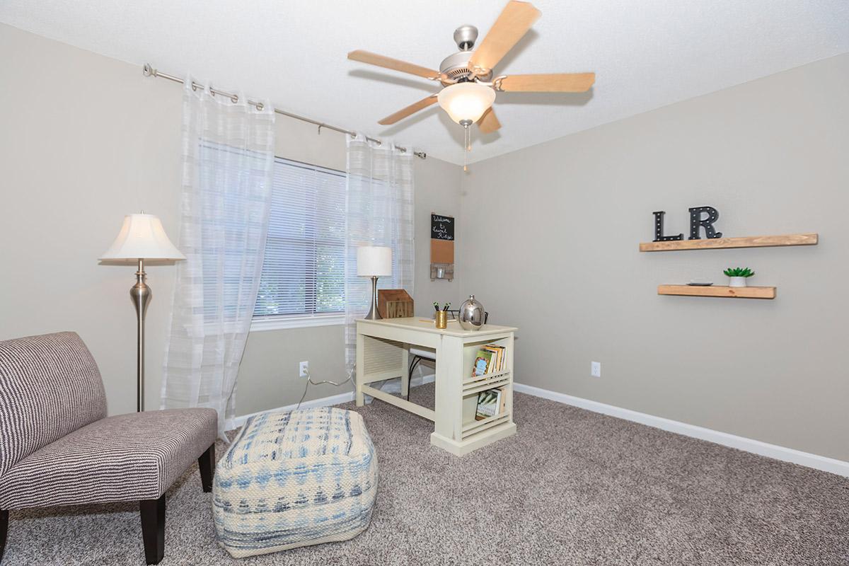 A Cozy Room with a Desk, Carpeted Floors and Ceiling Fan