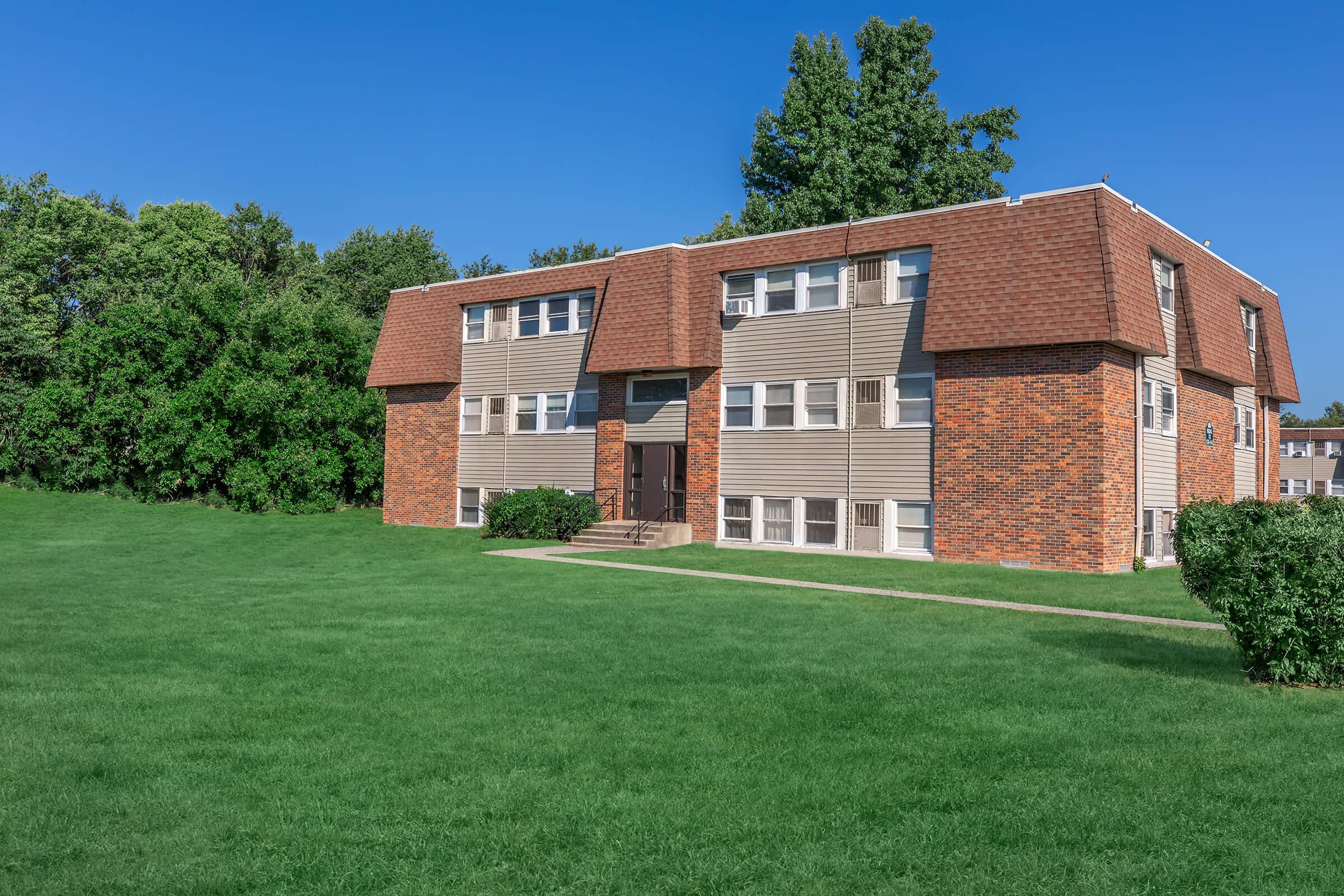 a large brick building with green grass in front of a house