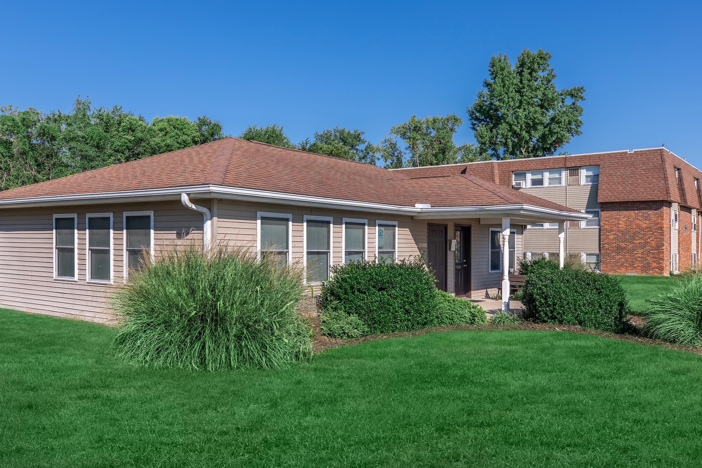 a large brick building with green grass in front of a house