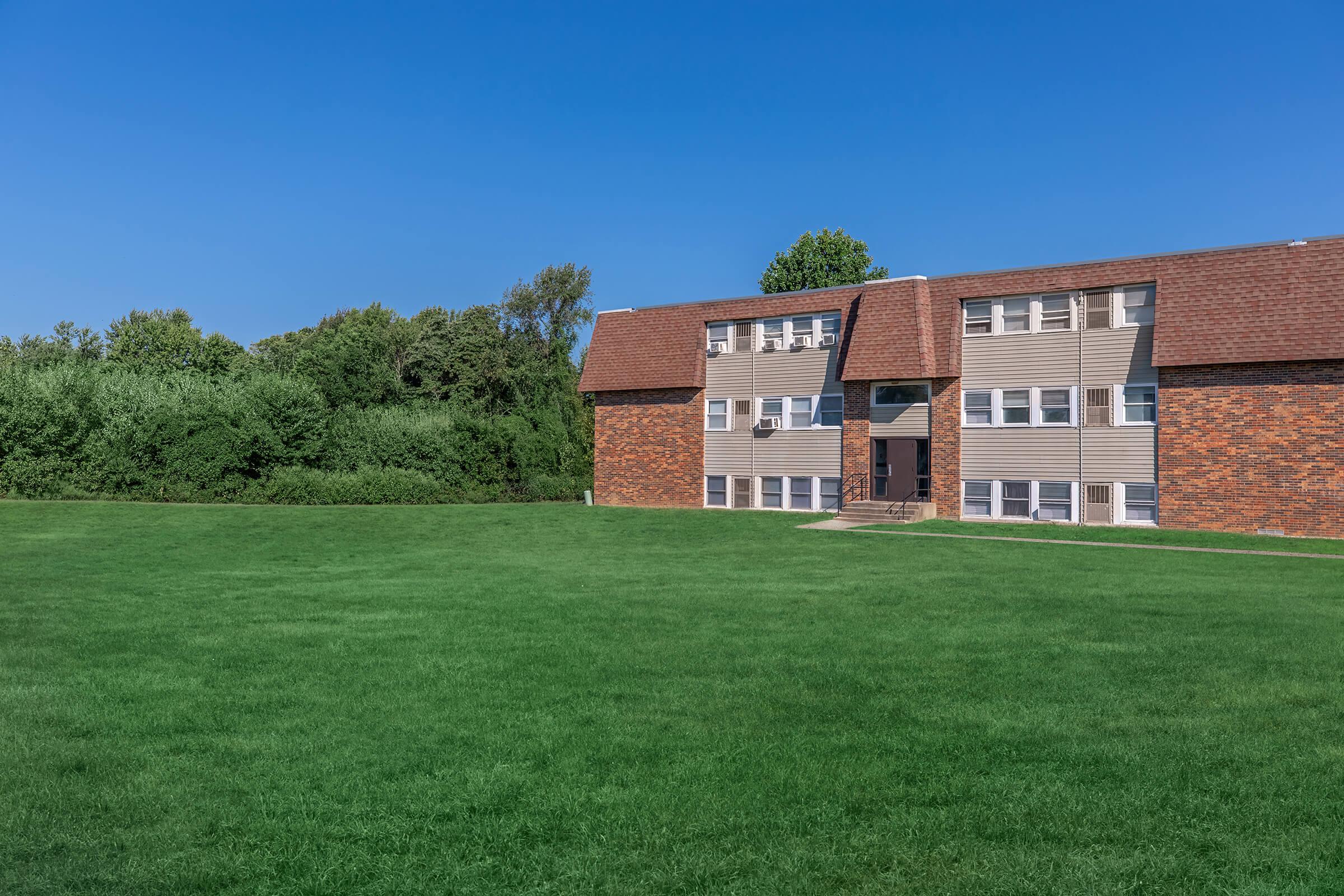 a large brick building with a grassy field