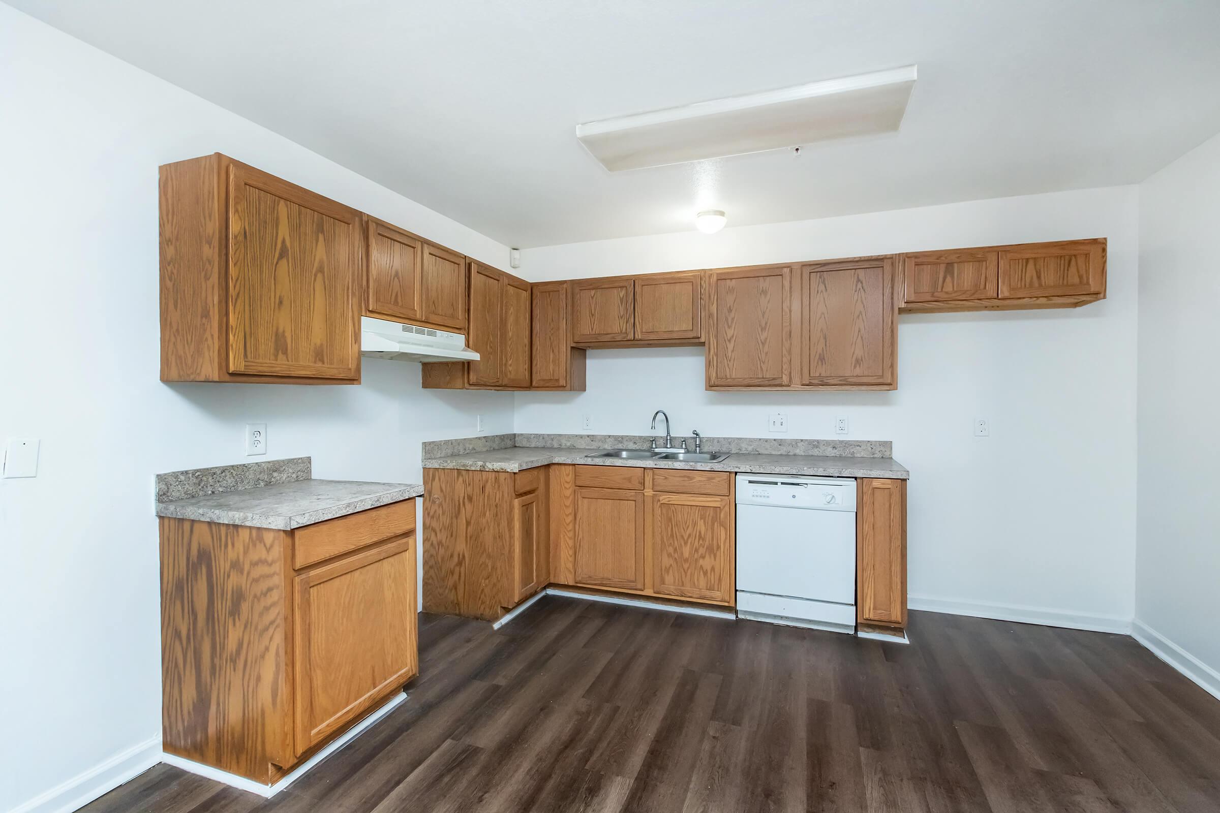 a kitchen with wooden cabinets and a hard wood floor