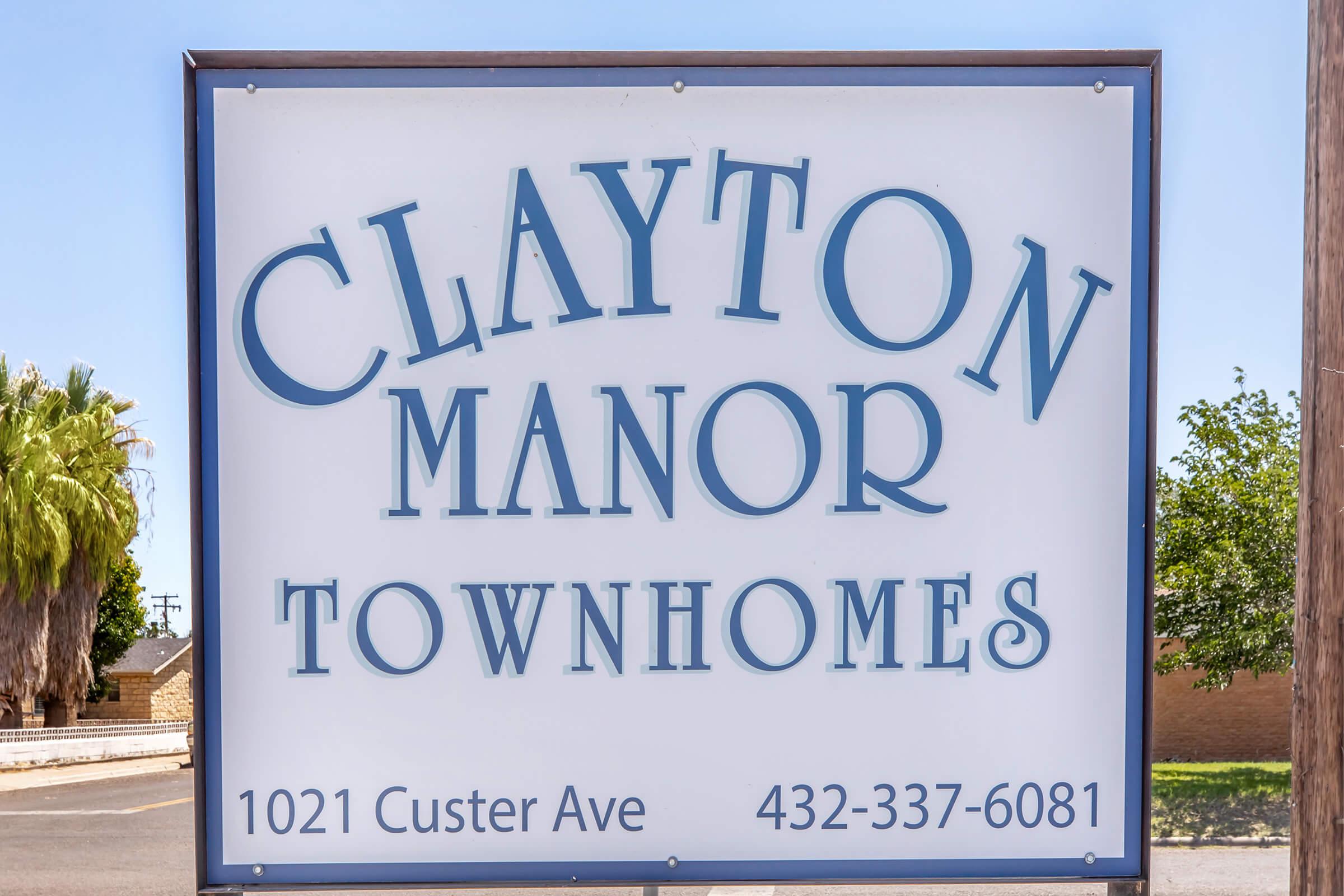 Sign for Clayton Manor Townhomes, displaying the name prominently at the top, with the address "1021 Custer Ave" and a phone number "432-337-6081" below. The sign features a simple, clean design against a clear blue sky, suggesting a friendly and welcoming atmosphere for potential residents.