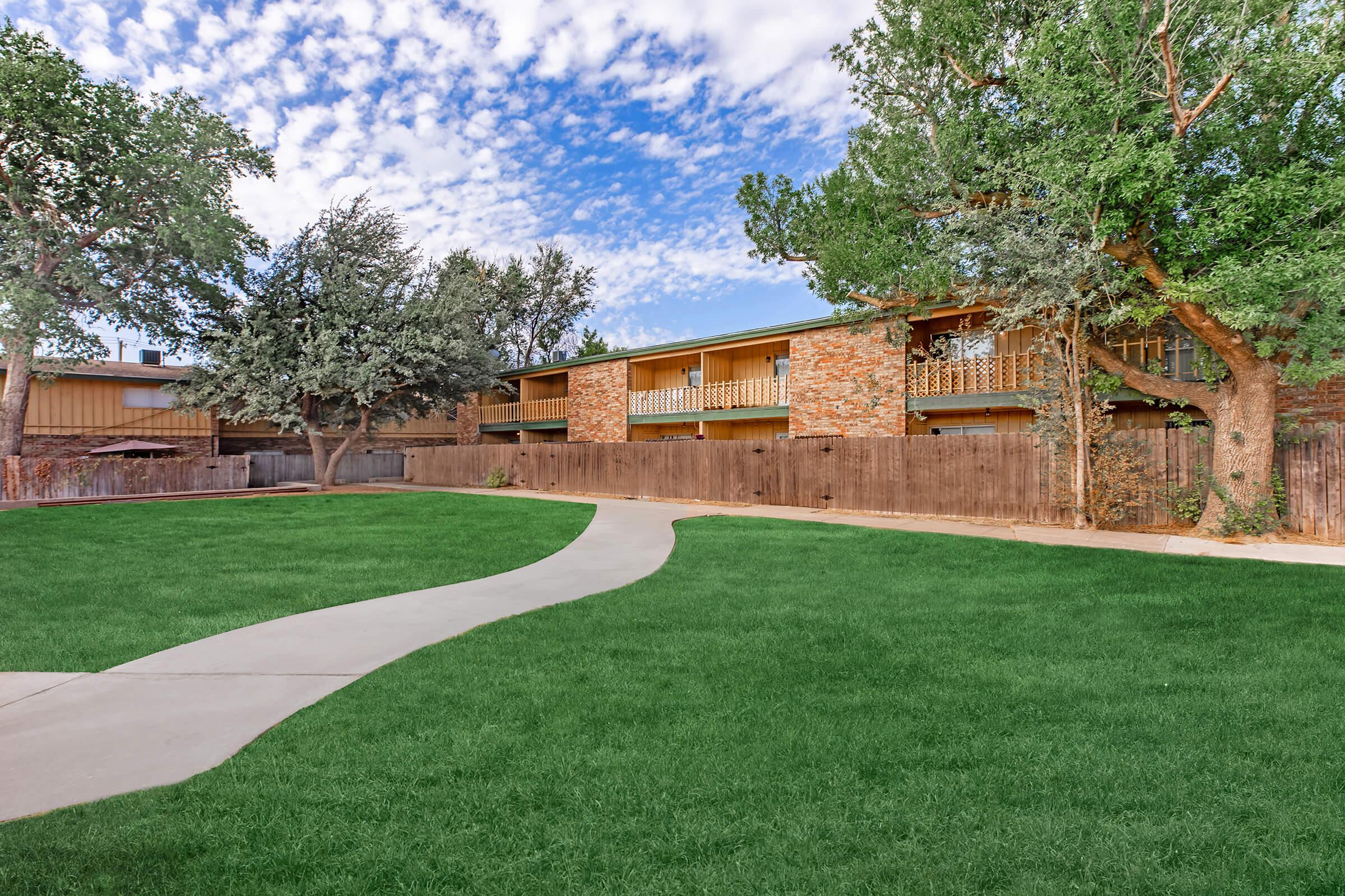 a large brick building with green grass in front of a house