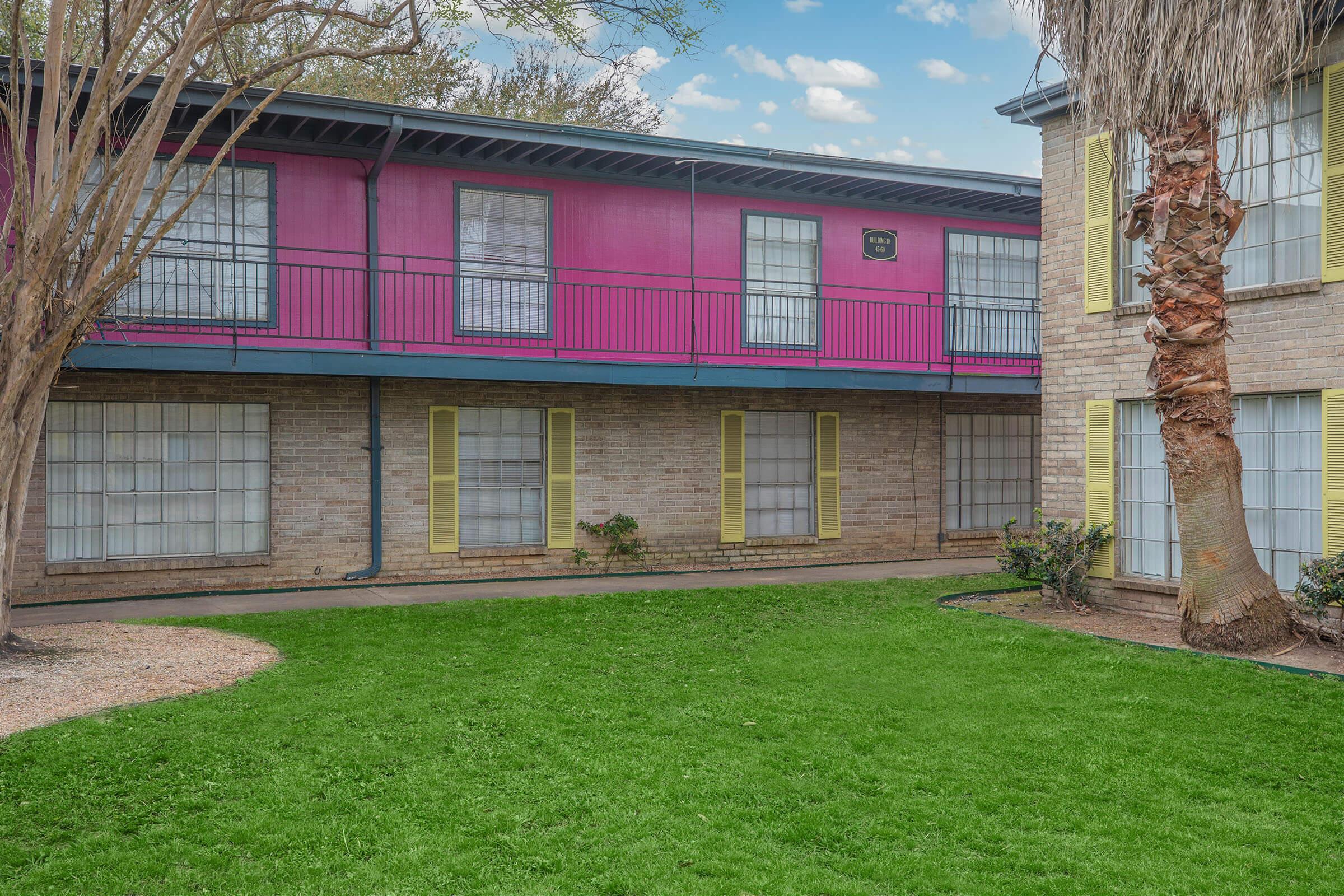 a large brick building with green grass in front of a house