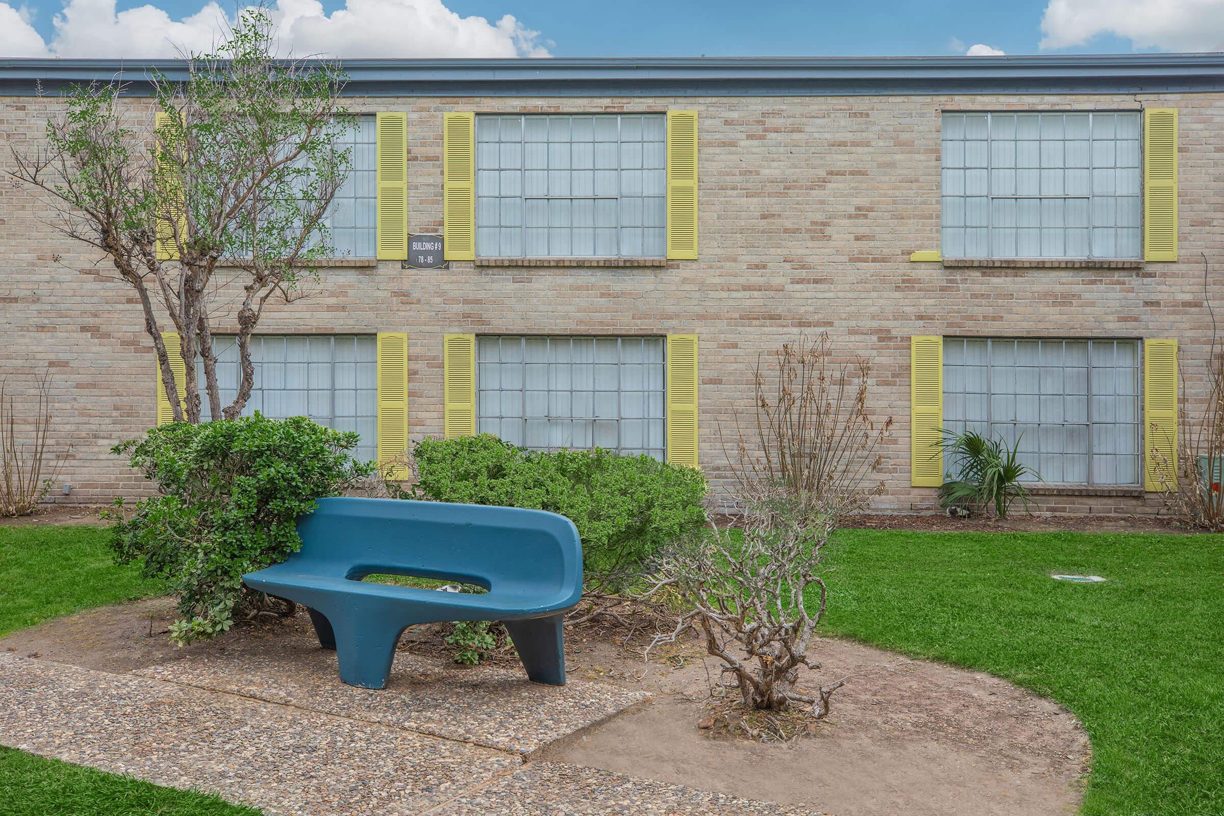 a green bench sitting in front of a brick building