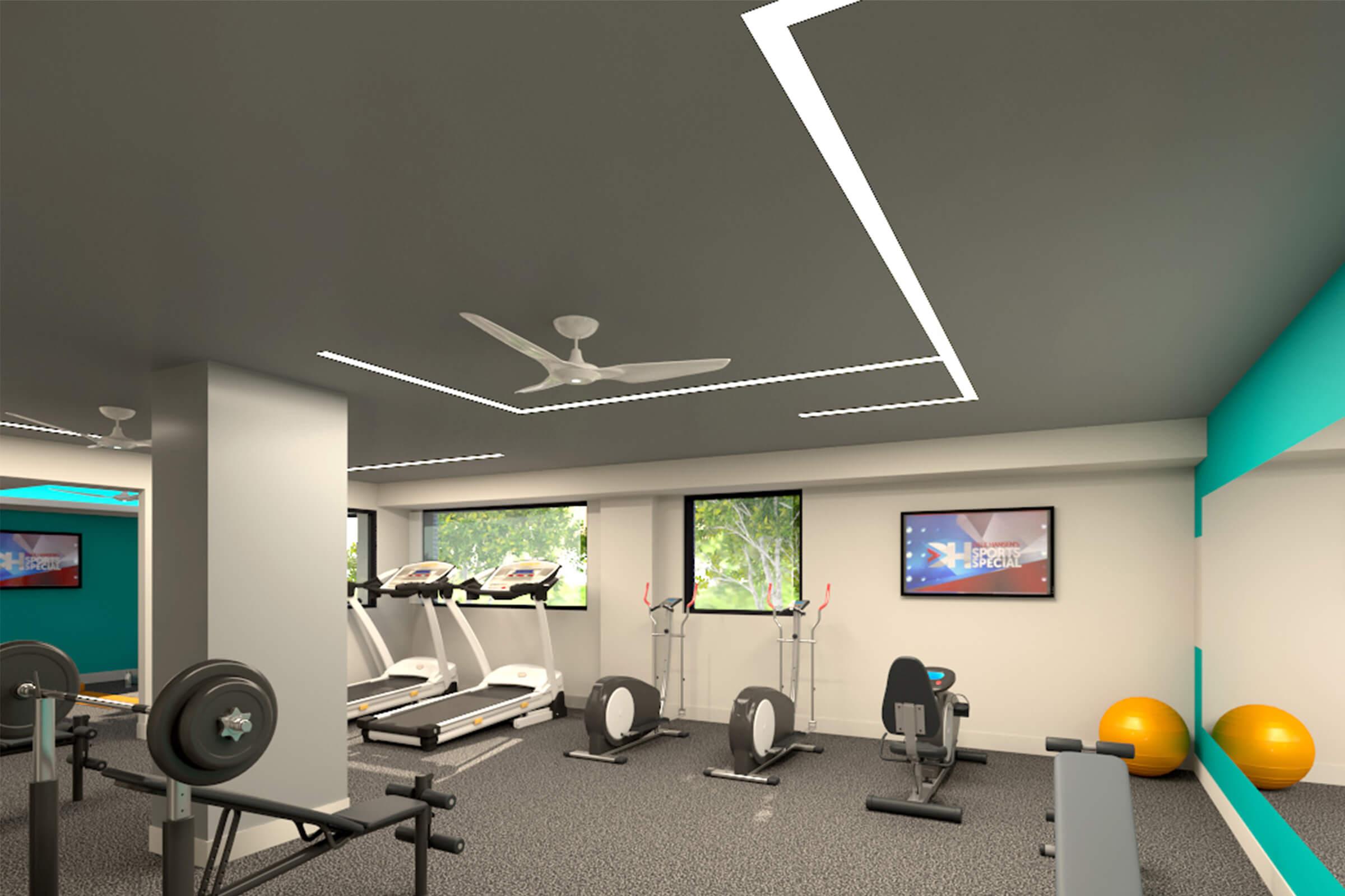 A modern gym interior featuring cardio machines like treadmills and ellipticals, exercise bikes, and fitness balls. Large windows allow natural light to enter, and there are sleek ceiling lights and a ceiling fan for ventilation. A motivational poster is visible on the wall.