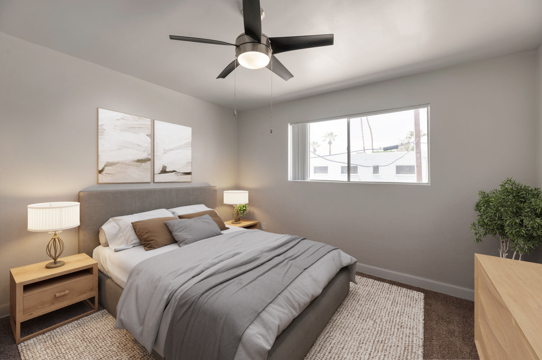 A modern, well-lit bedroom featuring a gray bed with decorative pillows, a large window with a view, two bedside lamps, and a small plant. Neutral colors dominate the decor, complemented by minimalist artwork on the walls and a wooden dresser. A ceiling fan adds to the cozy atmosphere.