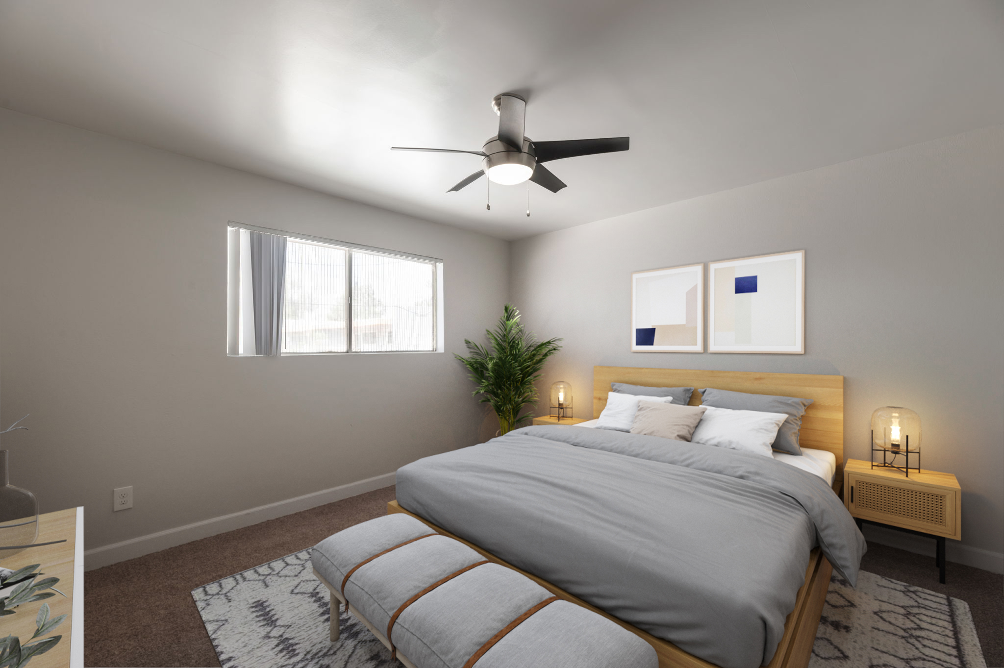A modern bedroom featuring a large bed with gray bedding and a bench at the foot. Natural light enters through a large window. The room includes a potted plant, a contemporary ceiling fan, and minimalist artwork on the walls. The floor is carpeted, creating a cozy atmosphere.