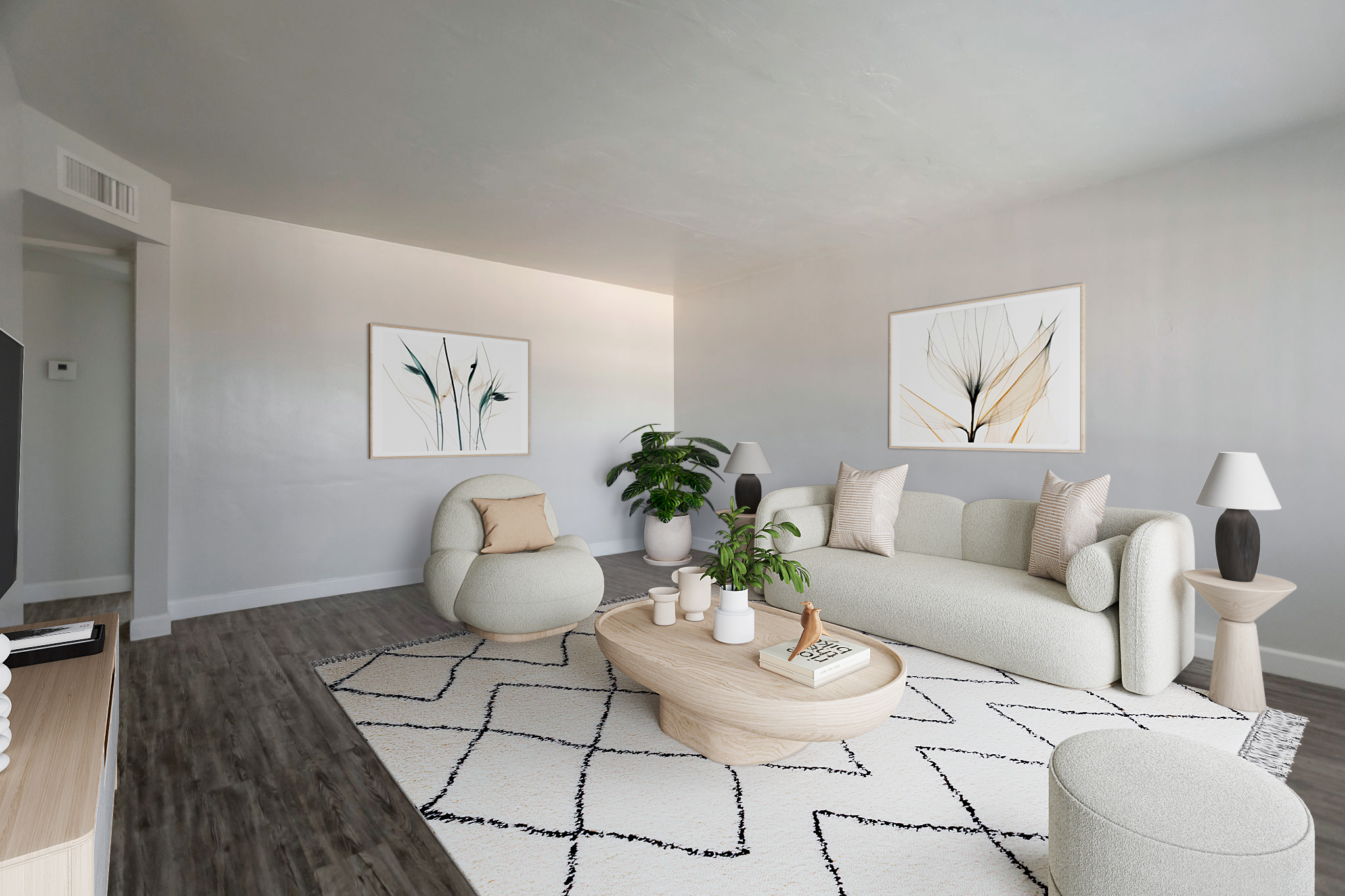 A modern living room featuring a light gray color scheme. It includes a curved sofa and an armchair, both in soft fabric, a wooden coffee table, and a decorative round pouf. The space is adorned with two abstract art pieces on the walls and a large green plant, creating a cozy and inviting atmosphere.