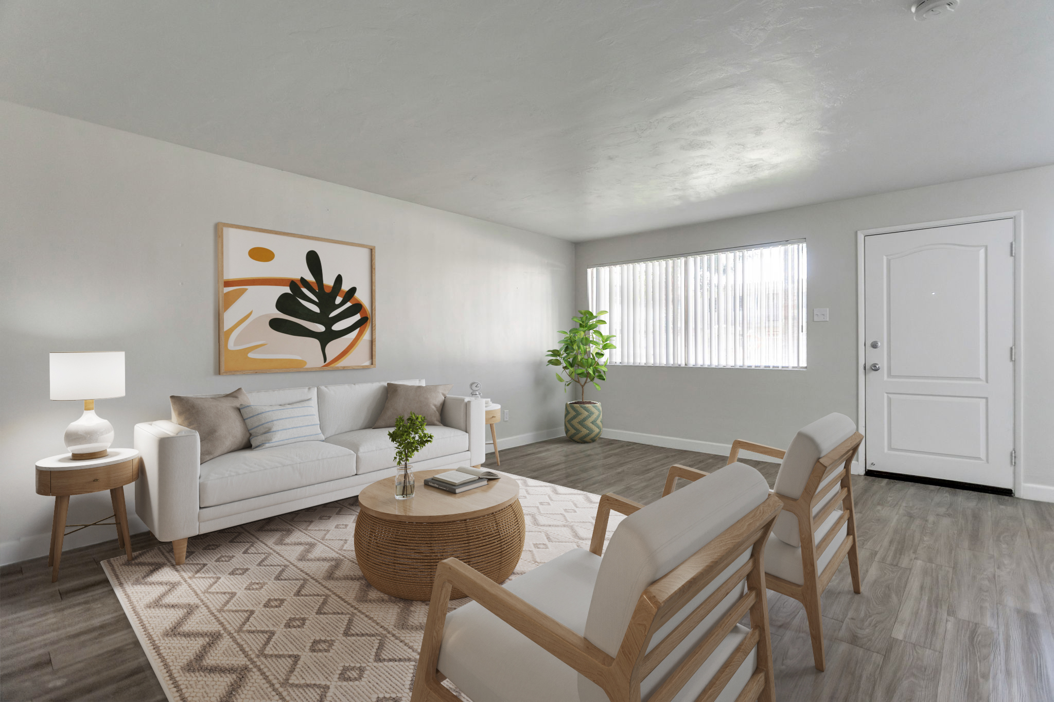 A modern living room featuring a white sofa with decorative pillows, two armchairs, a round coffee table, and a large piece of abstract art on the wall. A potted plant adds greenery, and natural light streams in through a window with vertical blinds. The decor has a neutral color palette and contemporary style.