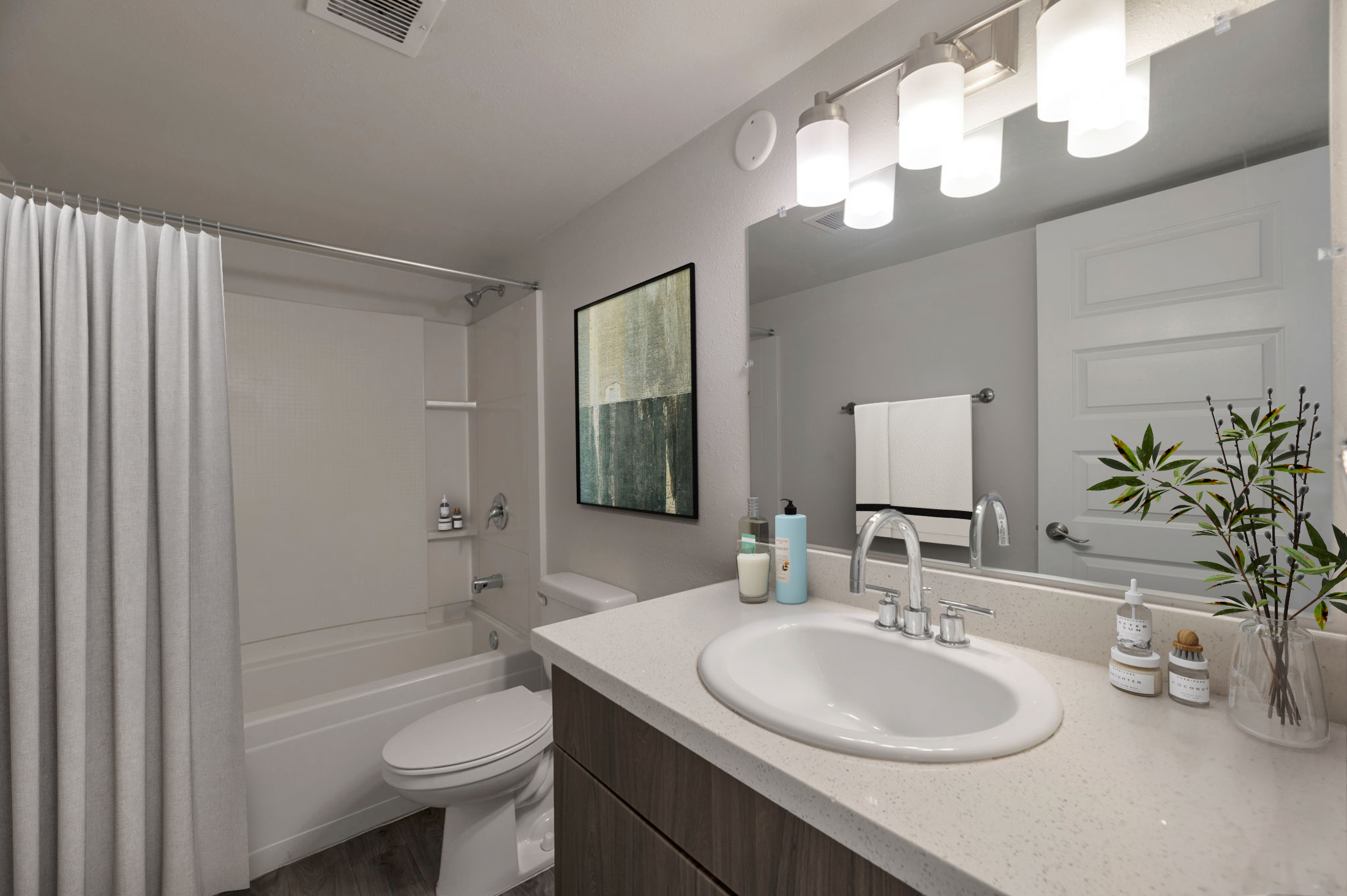 A modern bathroom featuring a white bathtub with a shower curtain, a large mirror with bright lighting, a sink with a countertop, and neatly arranged toiletries. The walls are light-colored, and there’s a decorative plant and art on the wall, creating a clean and inviting space.