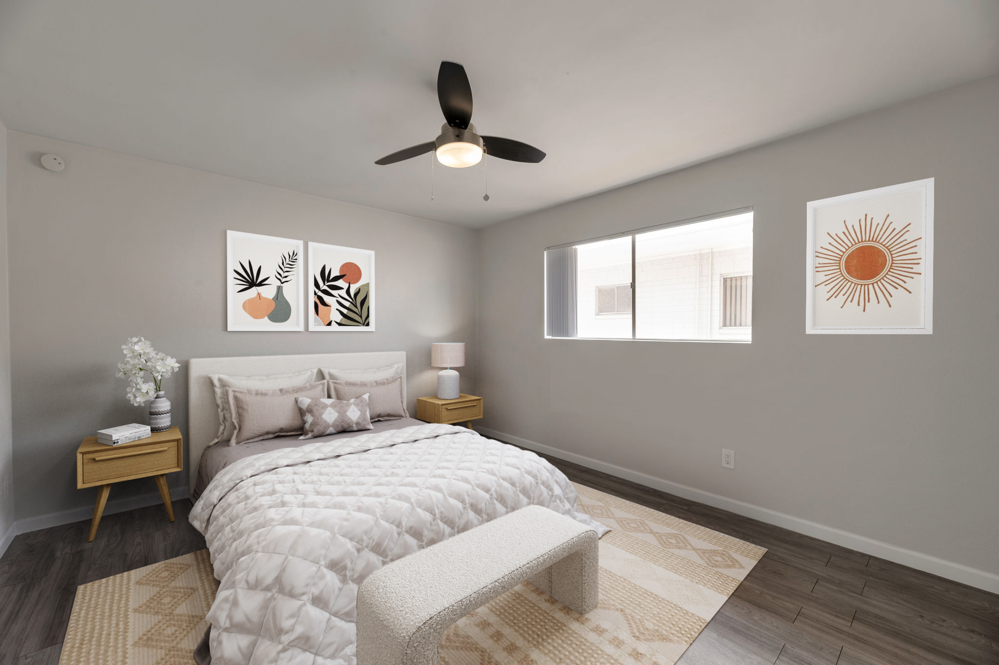 A modern, well-decorated bedroom featuring a light-colored bed with a textured quilt, decorative pillows, and a matching bench at the foot. Two wooden nightstands are on either side of the bed. The walls are adorned with three abstract art pieces, and a large window lets in natural light, illuminating the cozy space.