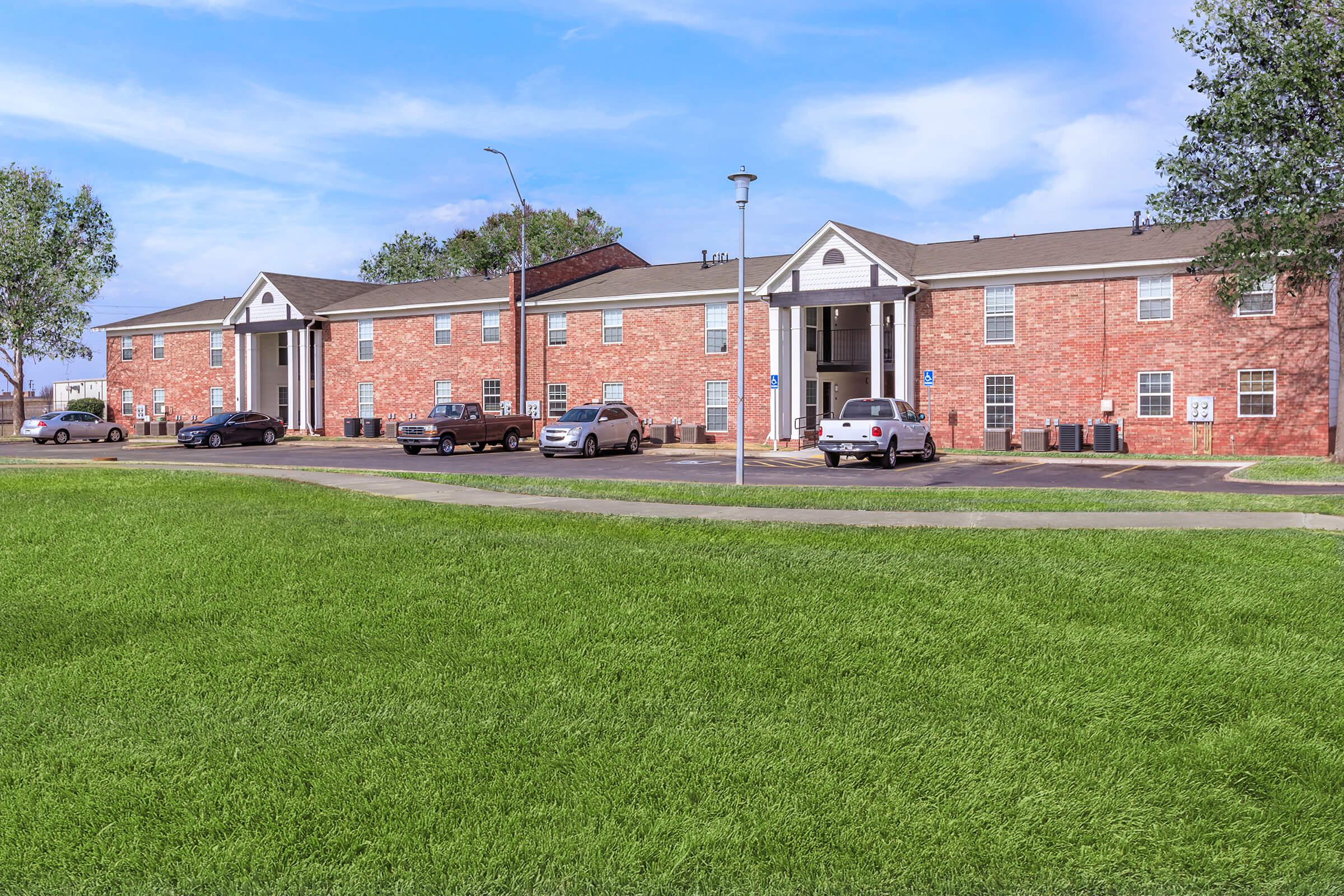 a large brick building with a grassy field