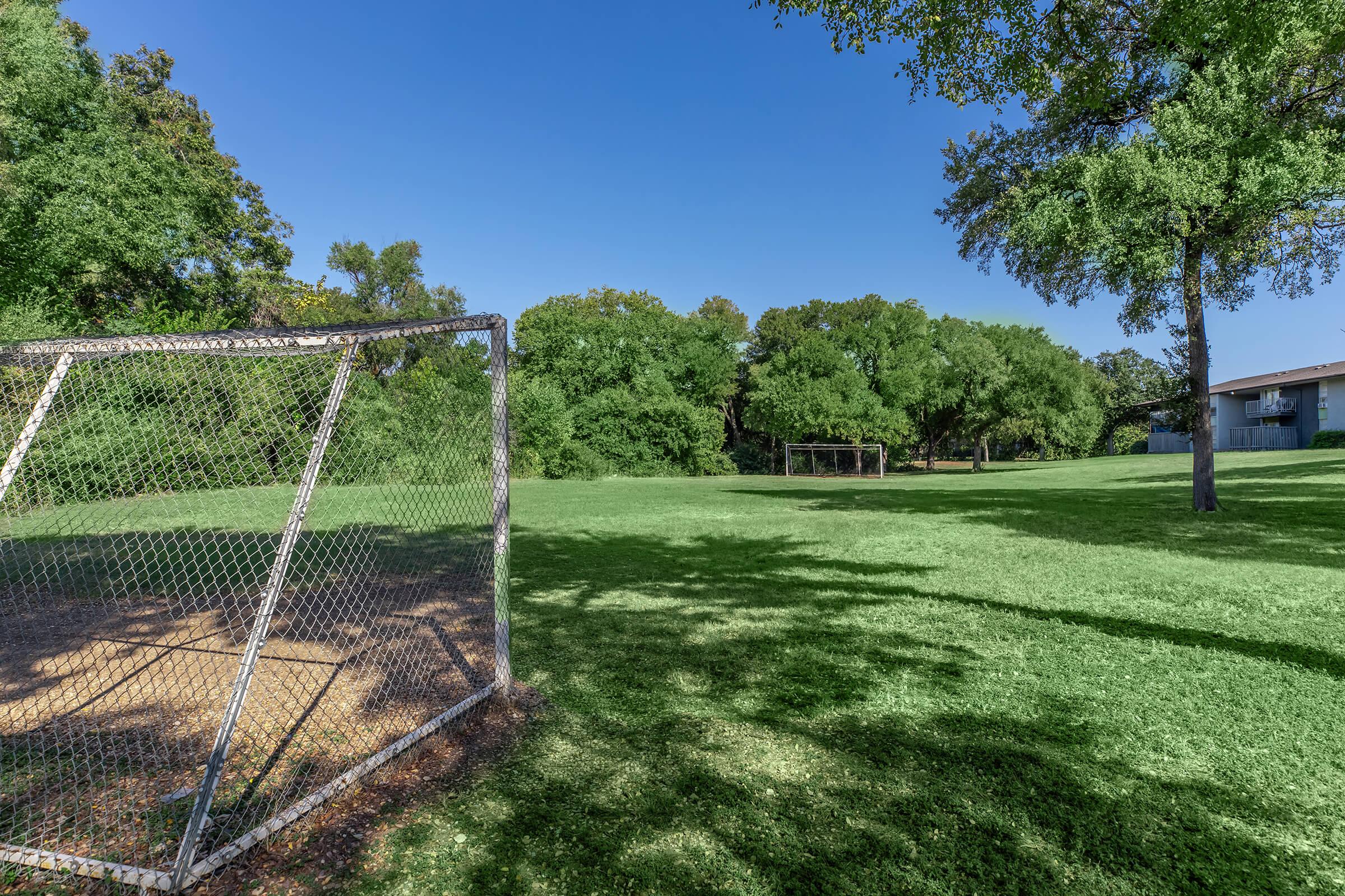 a large green field with trees in the background