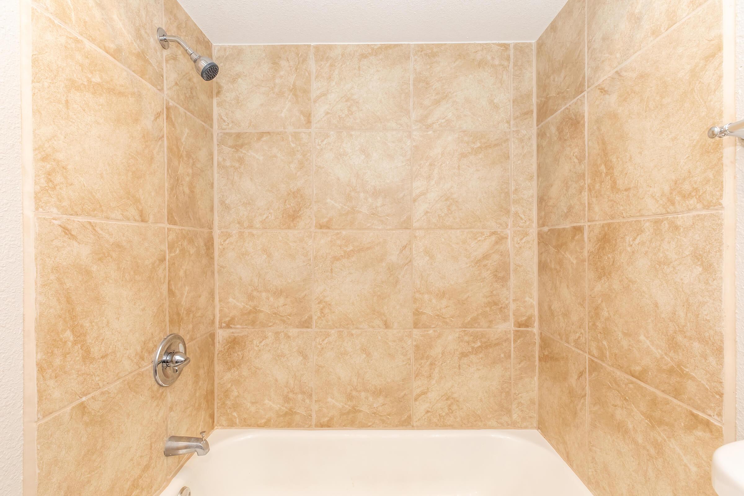 a brown tiled floor next to a shower