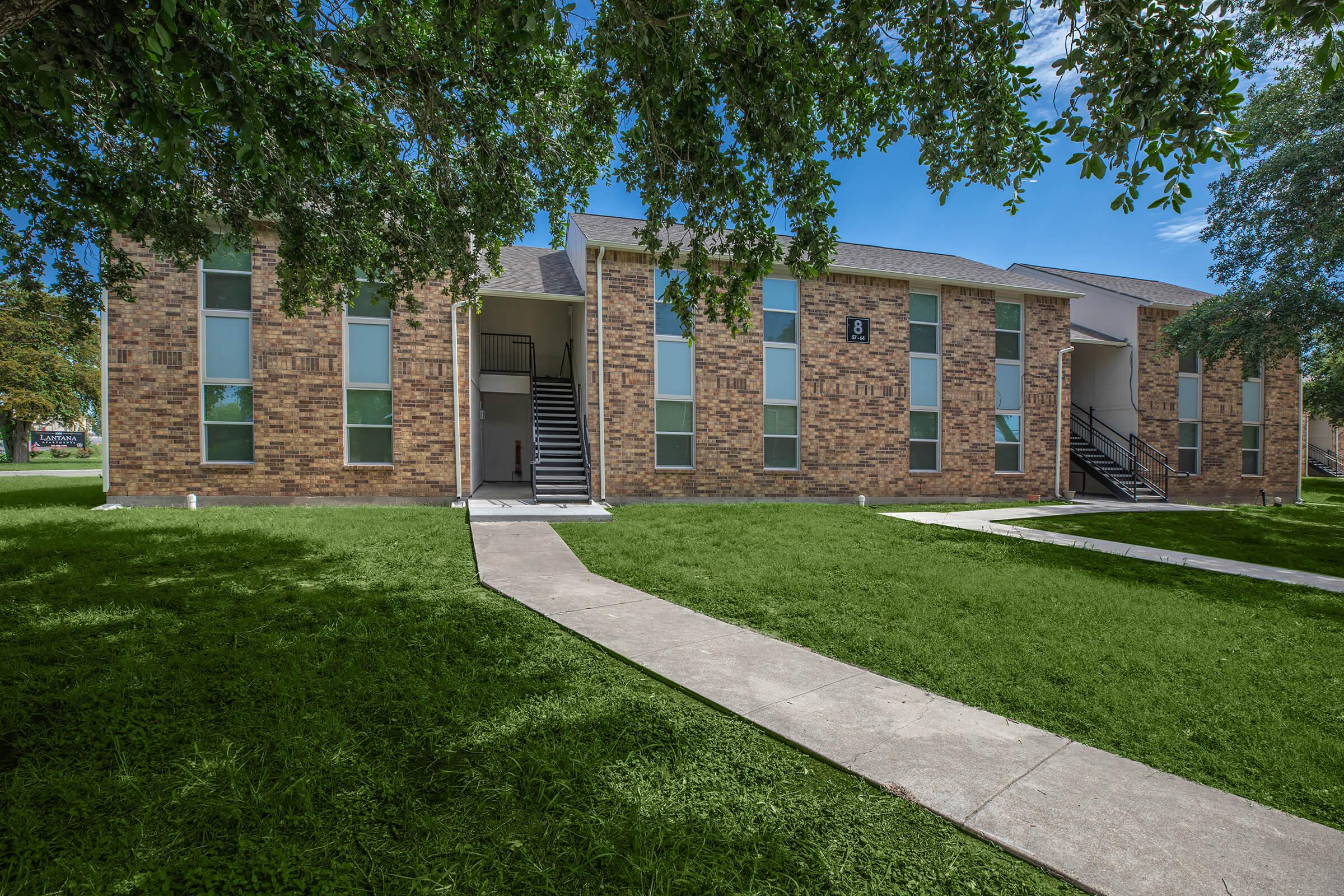 a large brick building with grass in front of a house