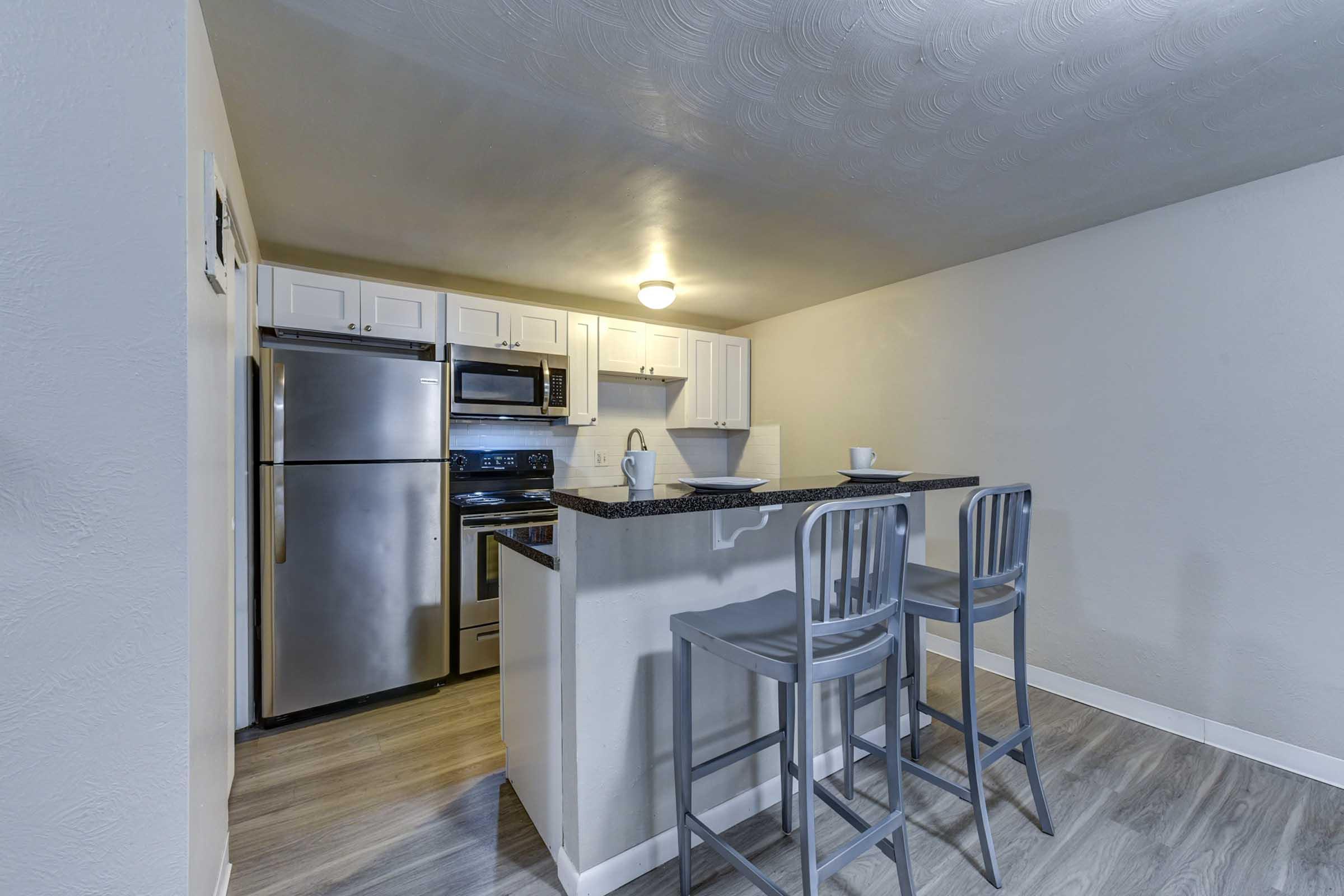 A modern kitchen featuring stainless steel appliances, including a refrigerator and oven, with dark countertops.
