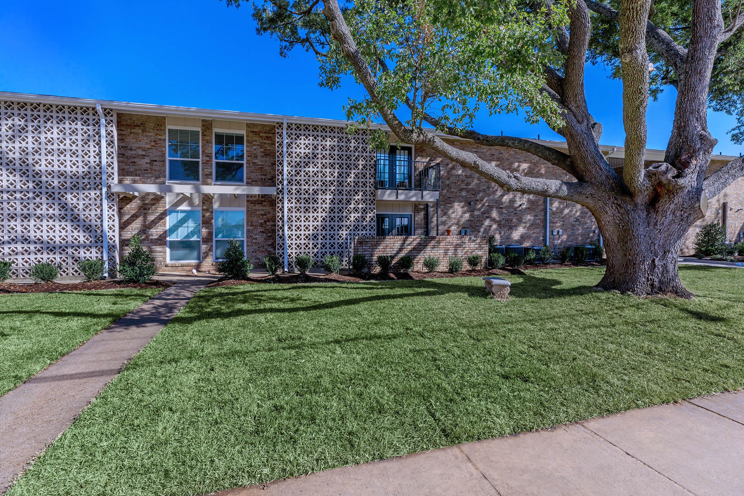 a large brick building with grass in front of a house