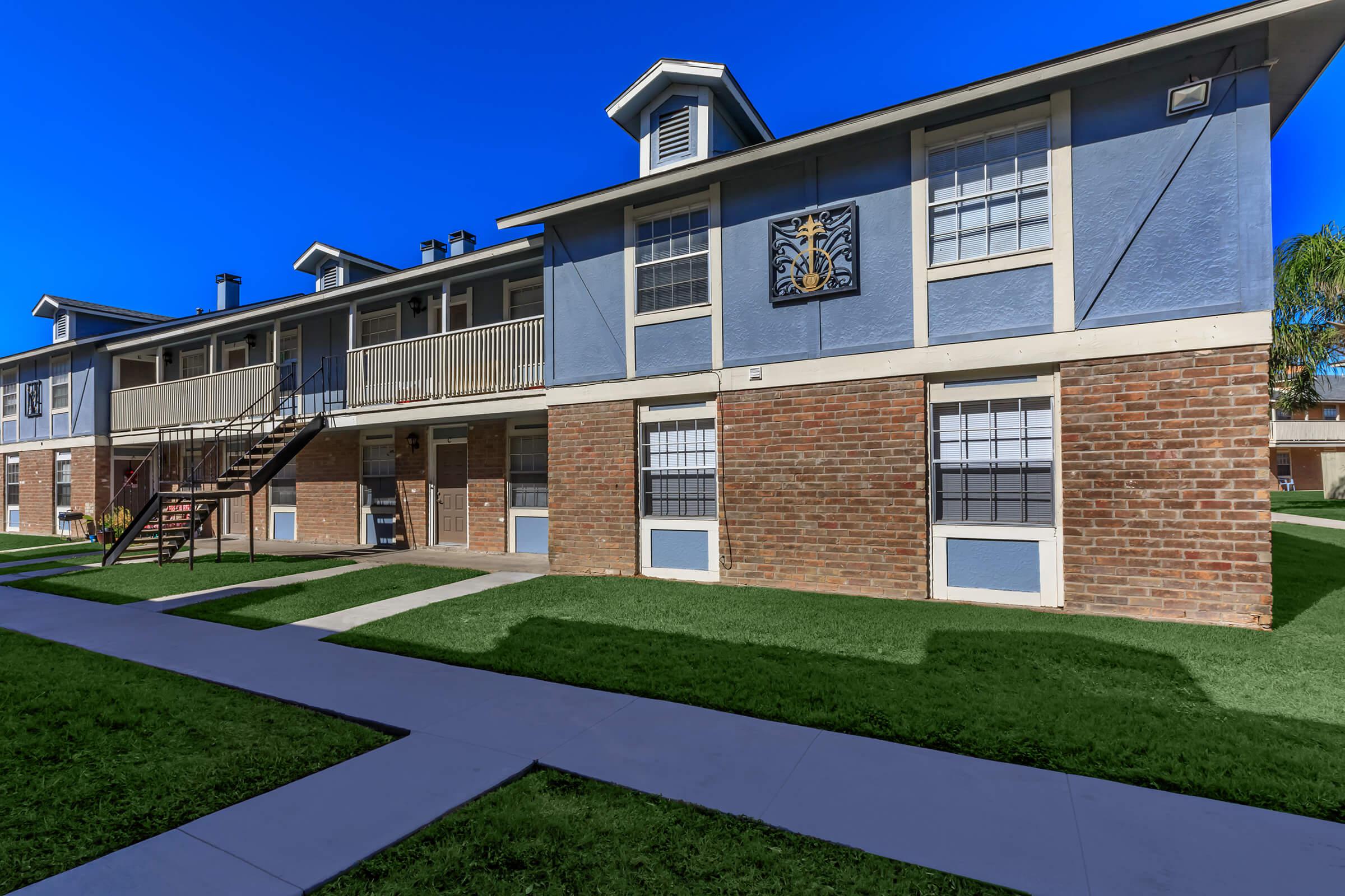a large brick building with grass in front of a house