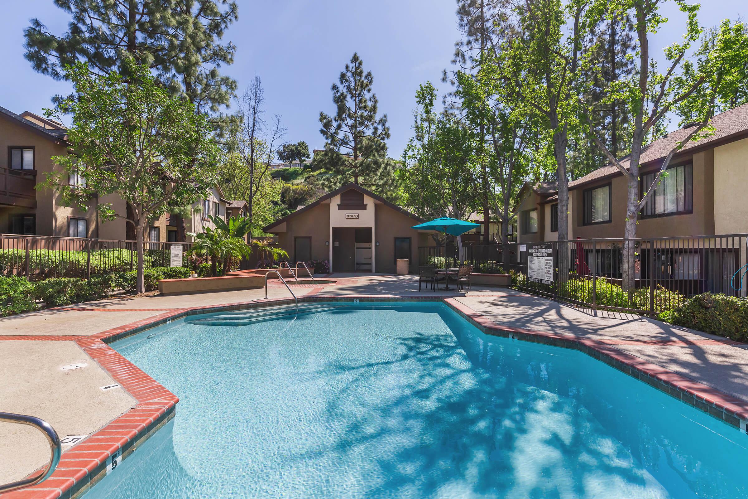 The community pool with a table and teal umbrella