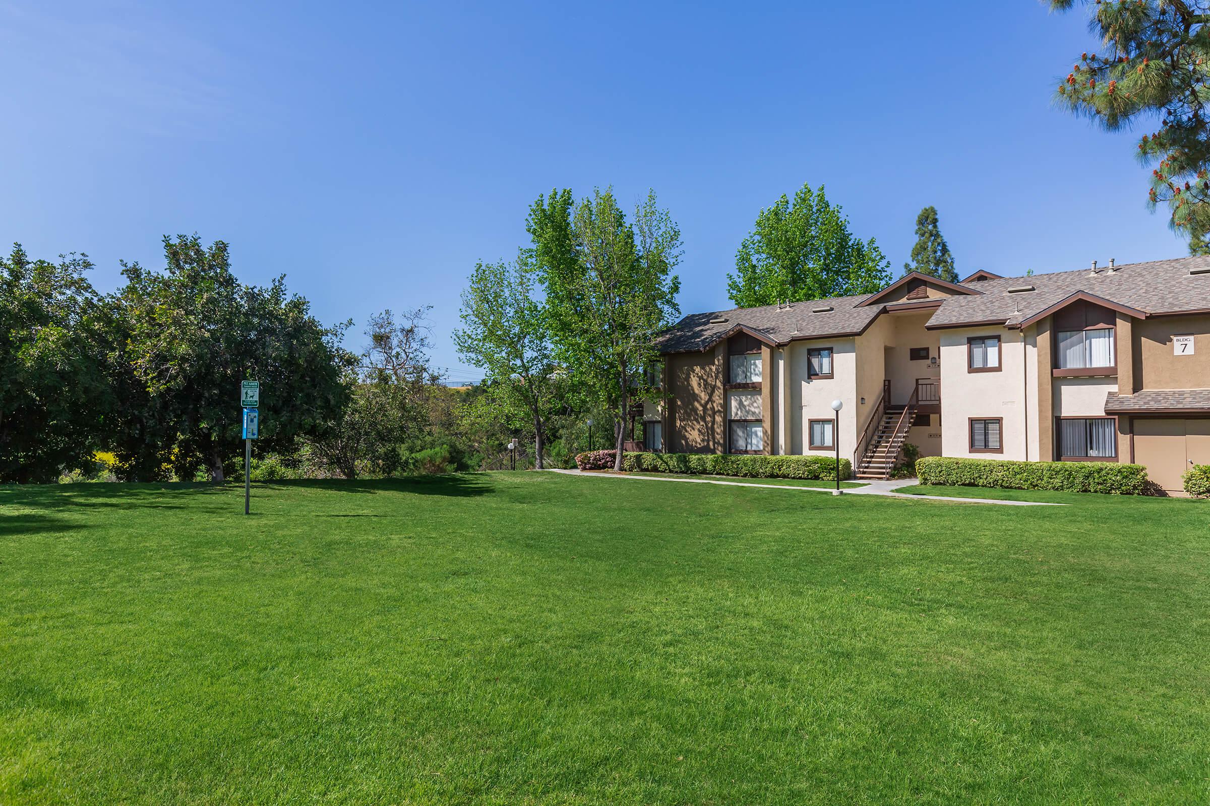 Emerald Court Apartment Homes community building with a green field