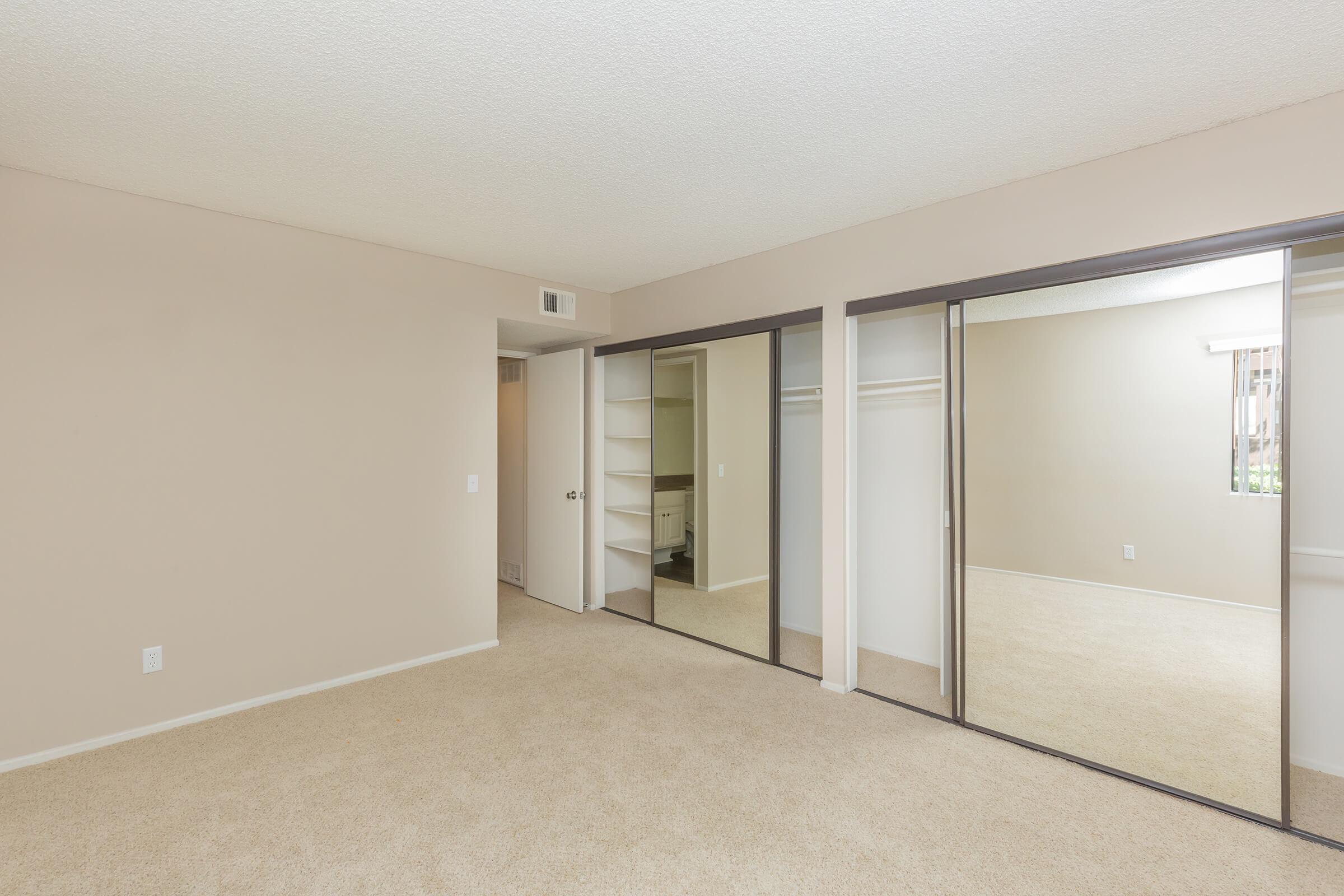 Bedroom with two sets of sliding mirror glass closet doors