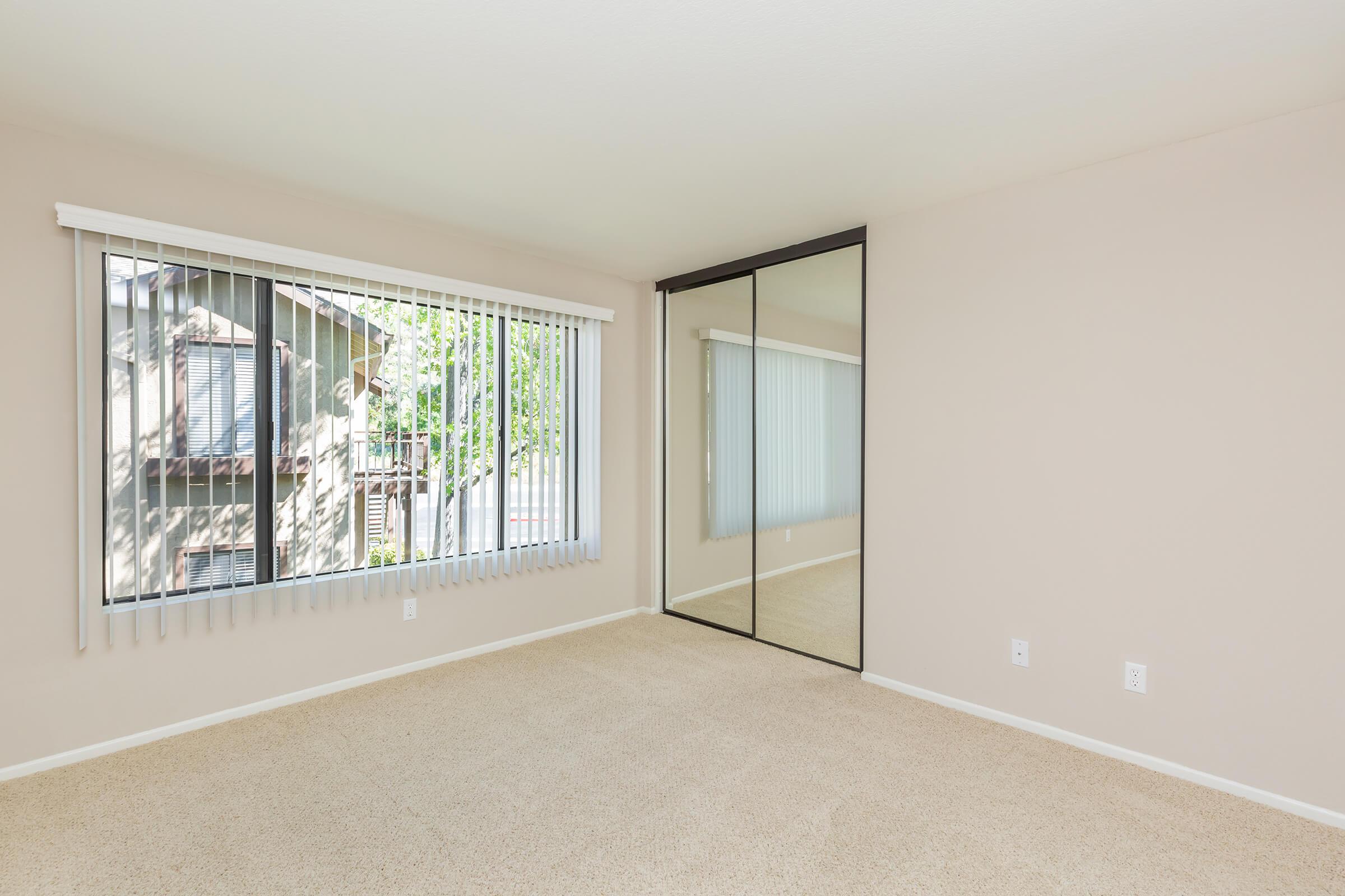 Unfurnished bedroom with sliding mirror glass closet doors
