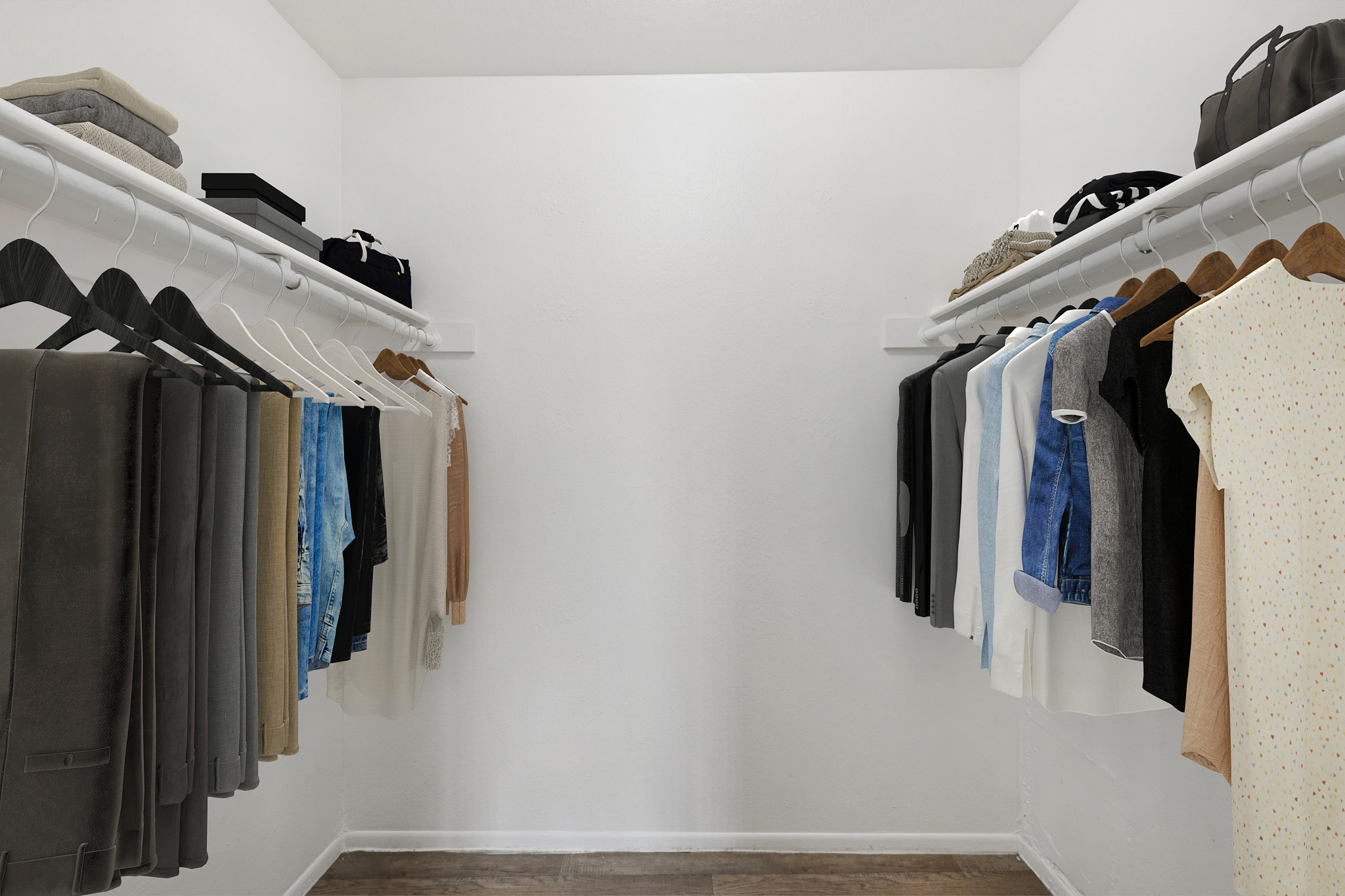 A neatly organized walk-in closet with two clothing racks. One side features hanging trousers and shirts in neutral tones, while the other side displays a variety of tops, including a light-colored dress. Shelves above hold boxes and bags, with a clean, minimalist design and white walls.