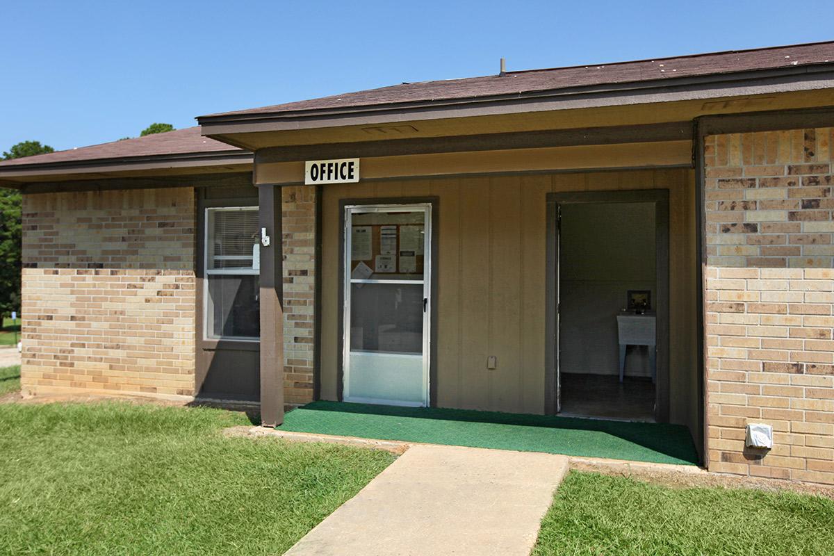 a large brick building with grass in front of a house with Darwin D. Martin House in the background