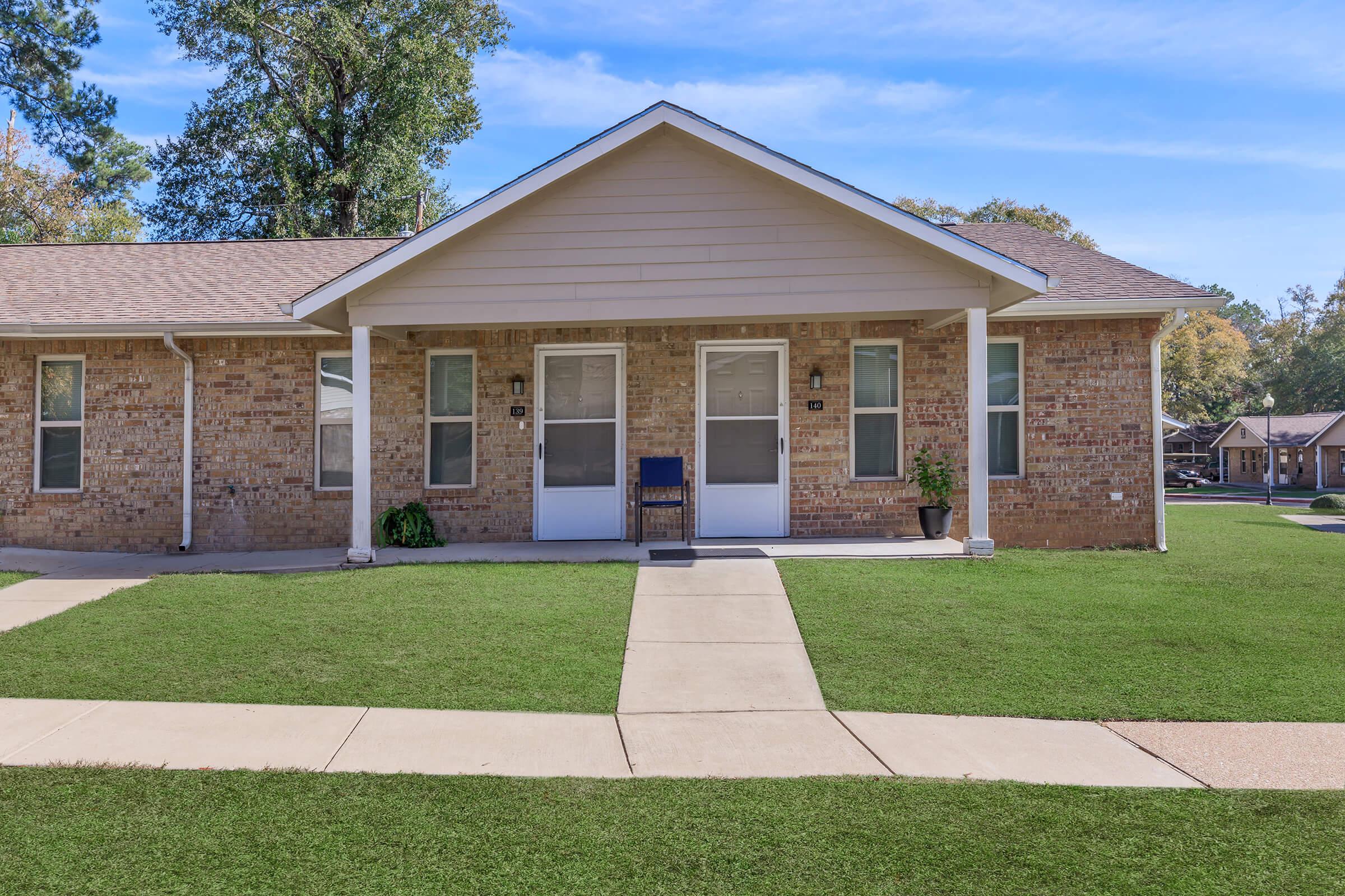 a house with a lawn in front of a brick building