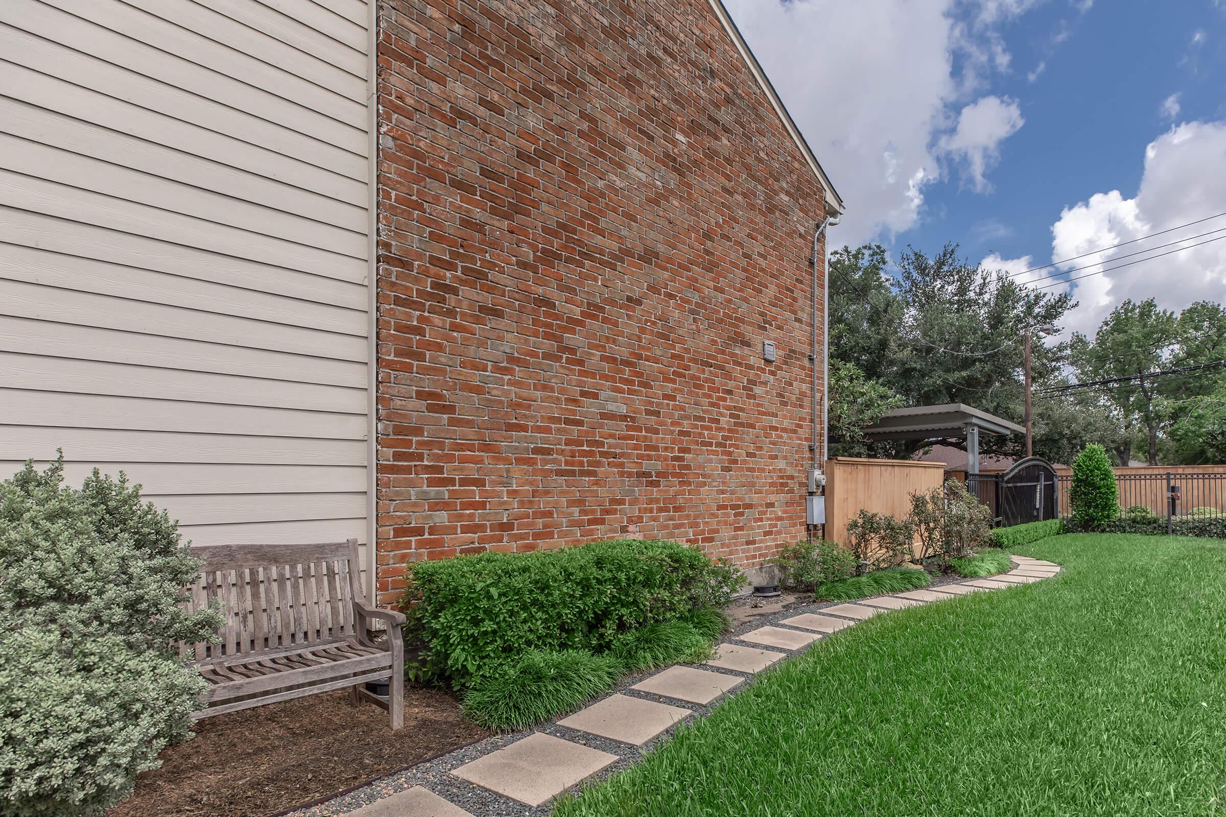 a house with bushes in front of a brick building