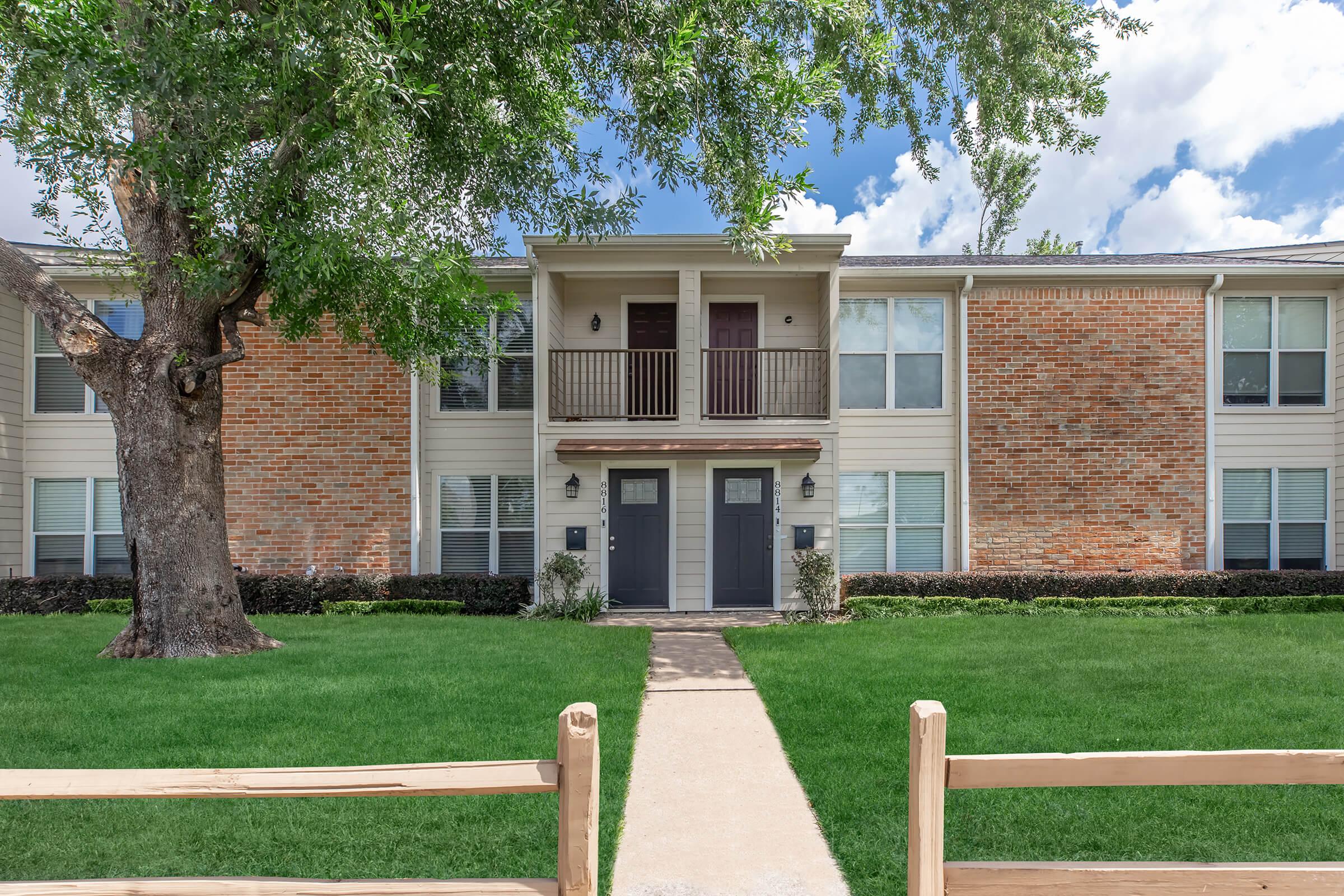 a house with a lawn in front of a brick building