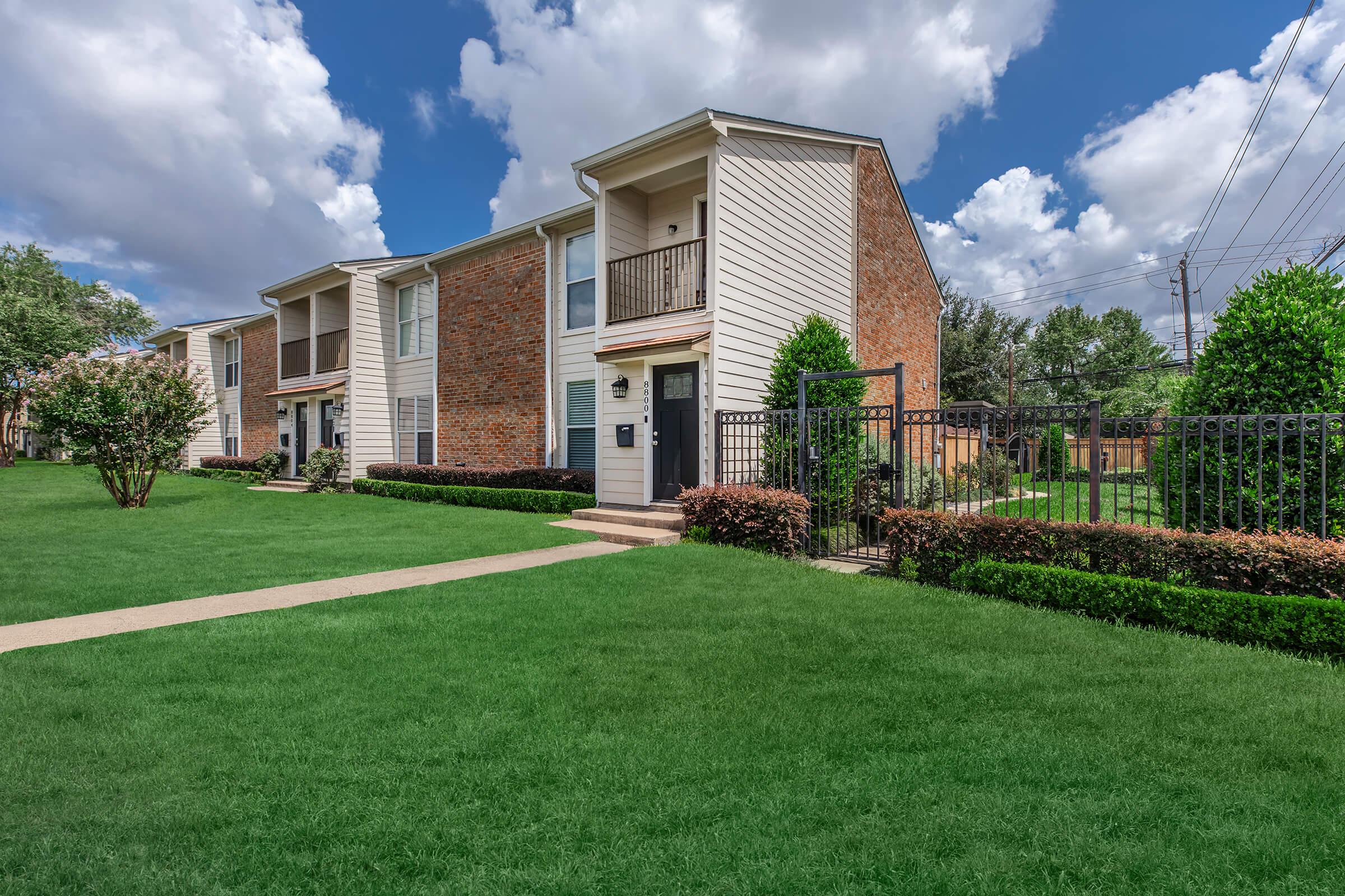 a large brick building with green grass in front of a house