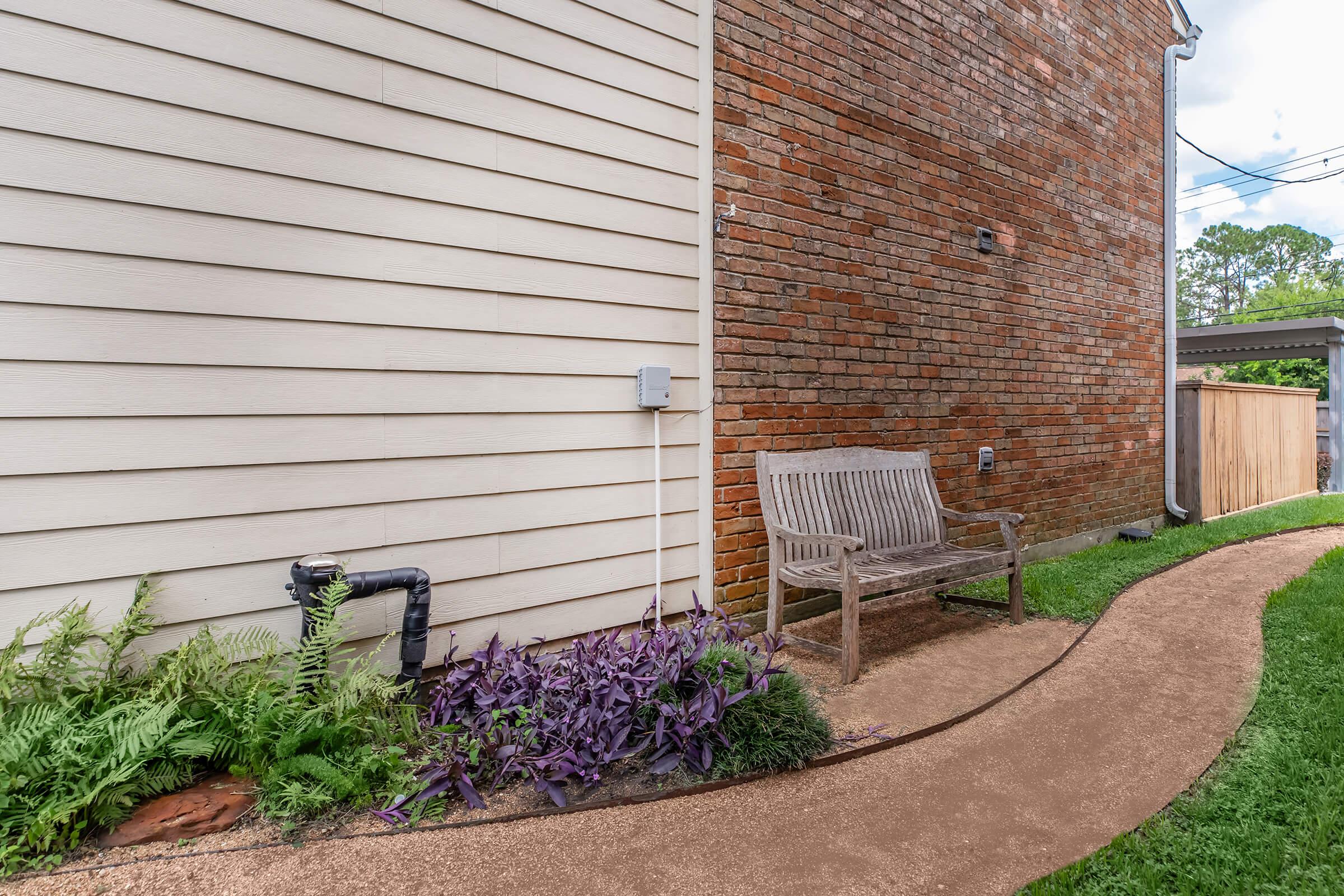 a house with bushes in front of a brick building