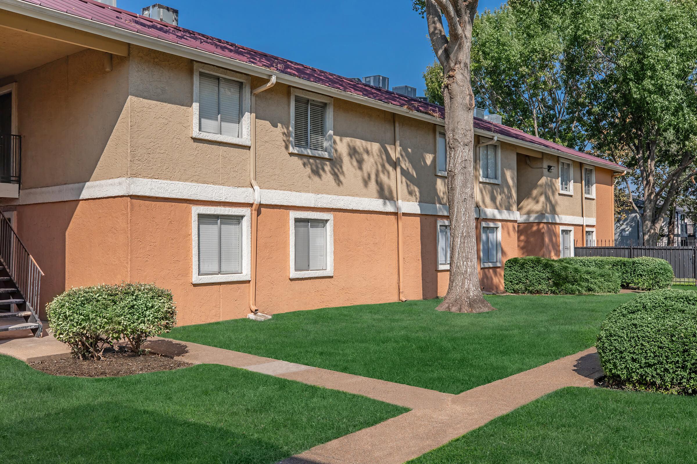 a house with a lawn in front of a brick building