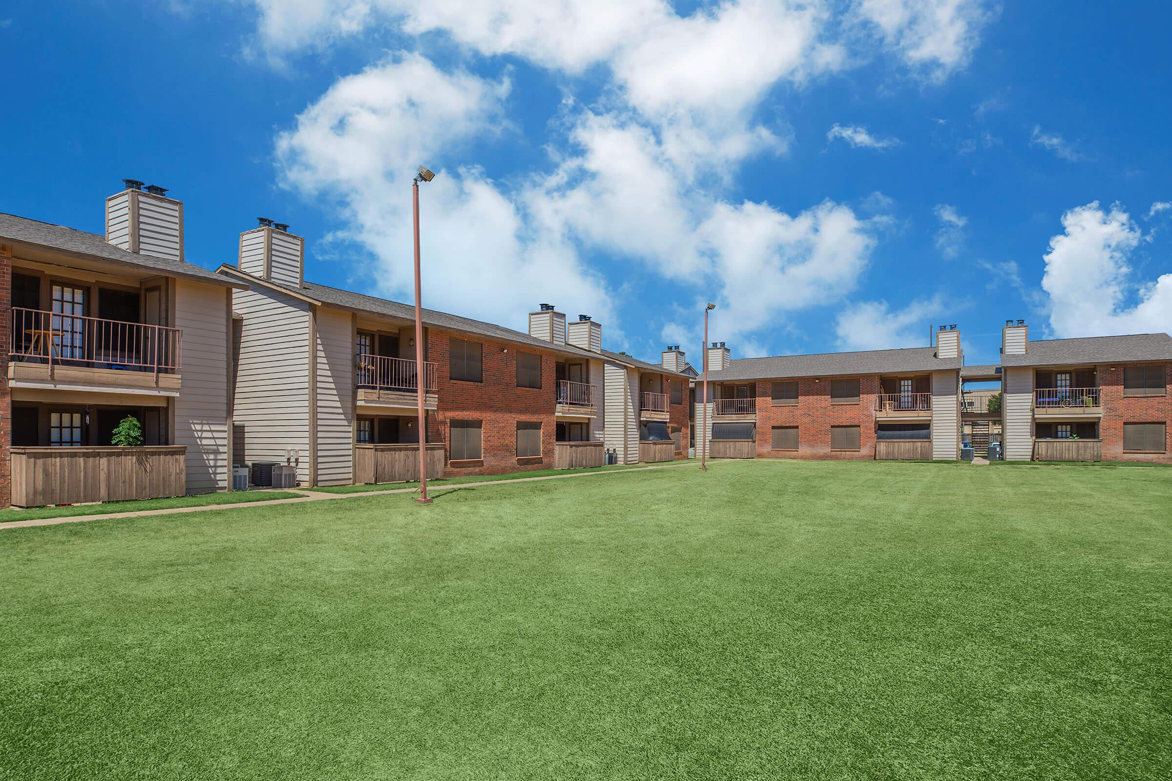 a large brick building with a grassy field