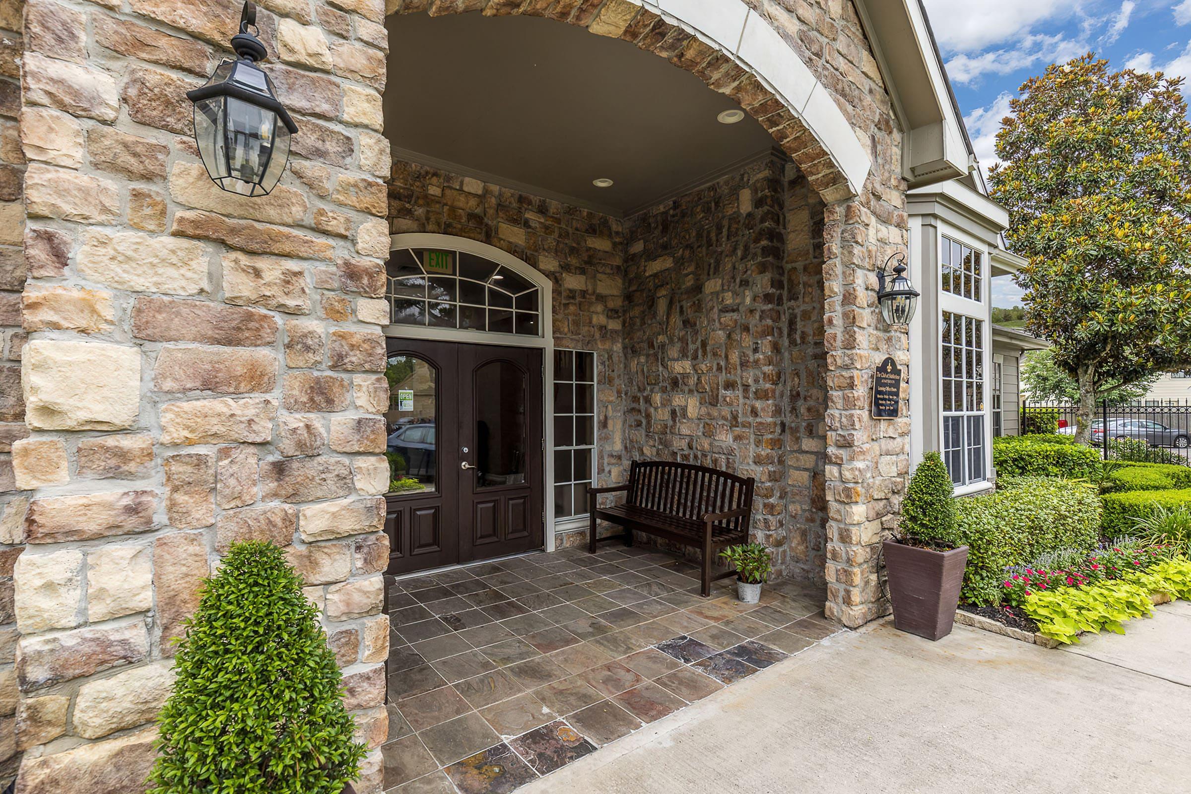 a stone building that has a bench in front of a brick wall