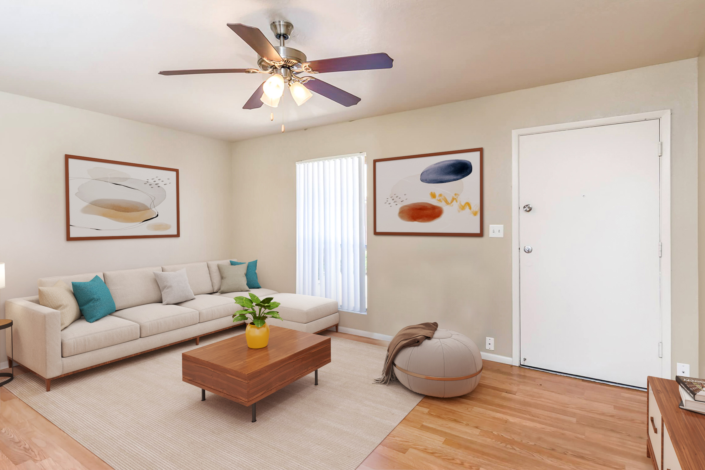 A bright and airy living room featuring a light-colored sofa with cushions, a wooden coffee table, and a small round ottoman. The room is decorated with two abstract framed artworks on the walls, and there’s a door and window with vertical blinds allowing natural light in. A potted plant adds a touch of greenery.