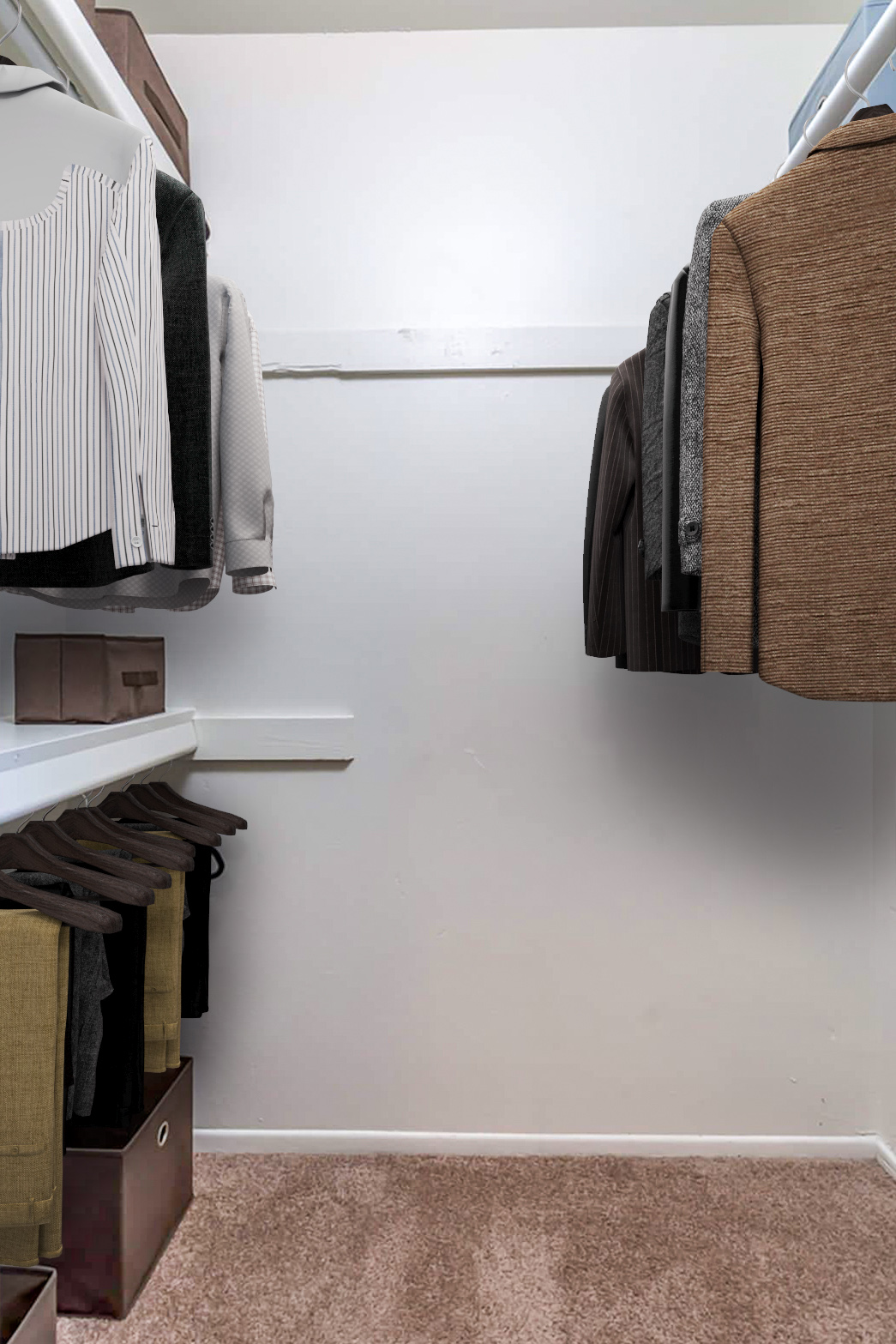 A well-organized closet featuring neatly hung clothes including shirts and coats, with shelving and storage boxes on the floor. The wall is bare and painted white, and the floor is carpeted.