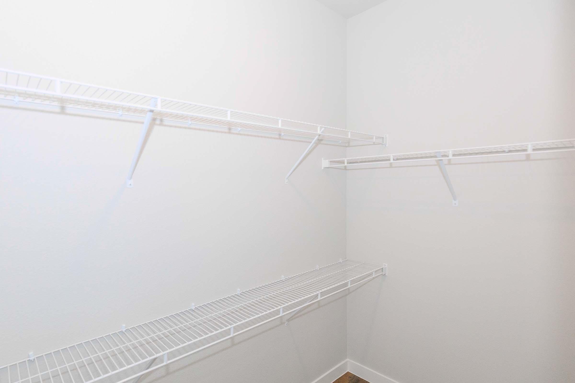 A spacious, empty closet with white wire shelving installed on the walls. The shelves are neatly organized without any items on them, and the walls are painted a light color, creating a clean and minimalist appearance.